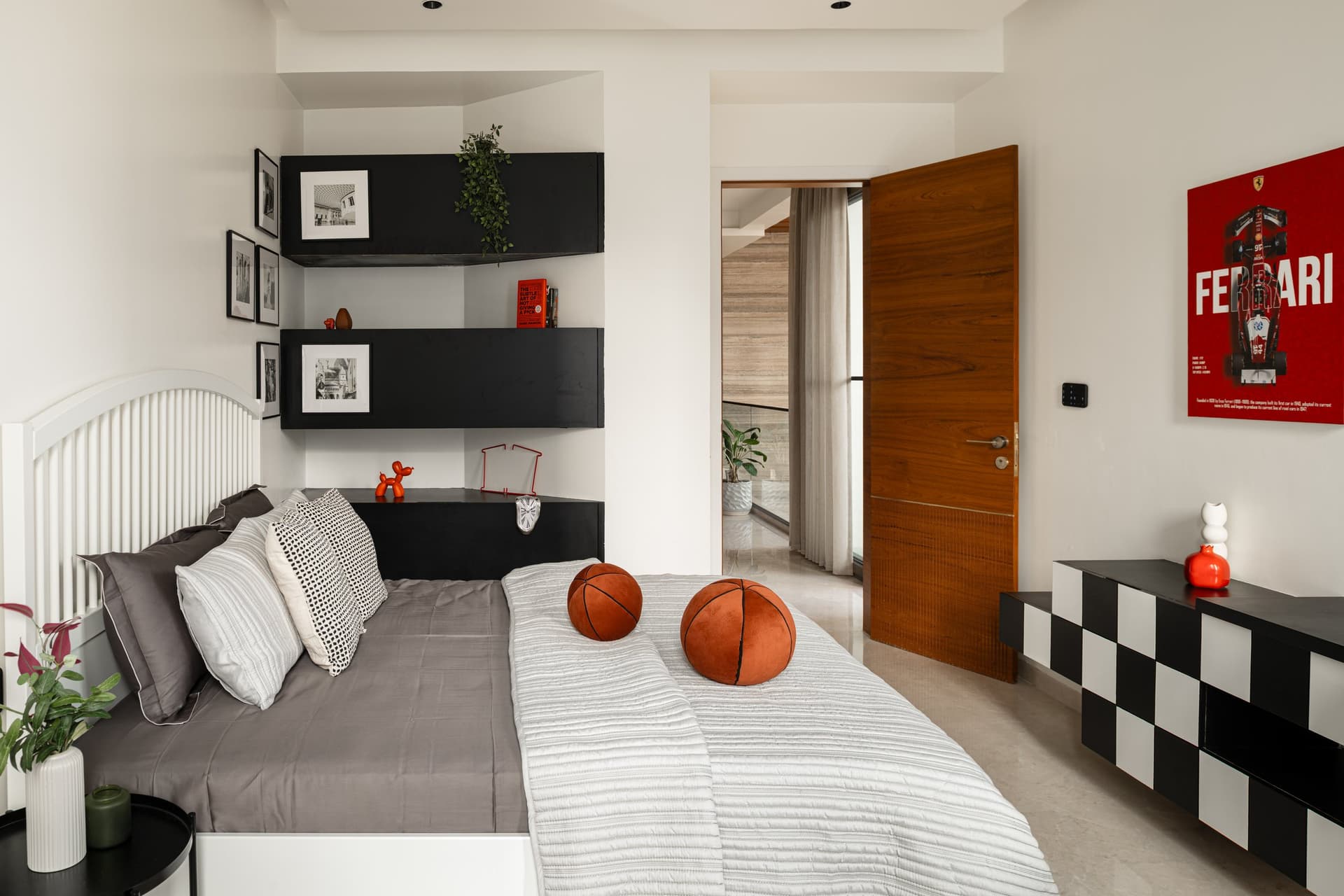 The younger son's bedroom, where a white slatted headboard and black floating shelves carry the room's graphic register