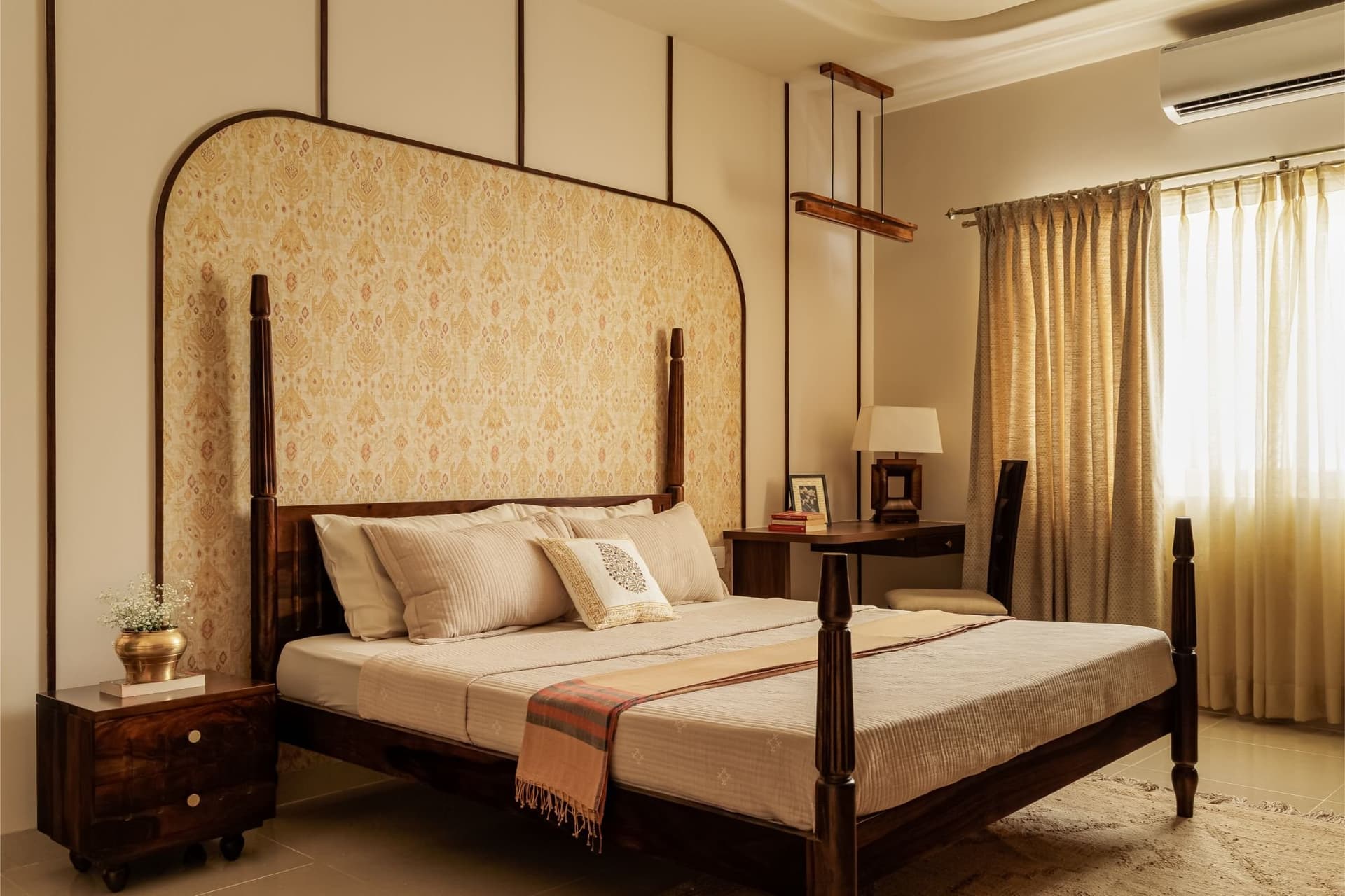 The master bedroom, anchored by a Sheesham four-poster framed within a saffron-patterned arched insert