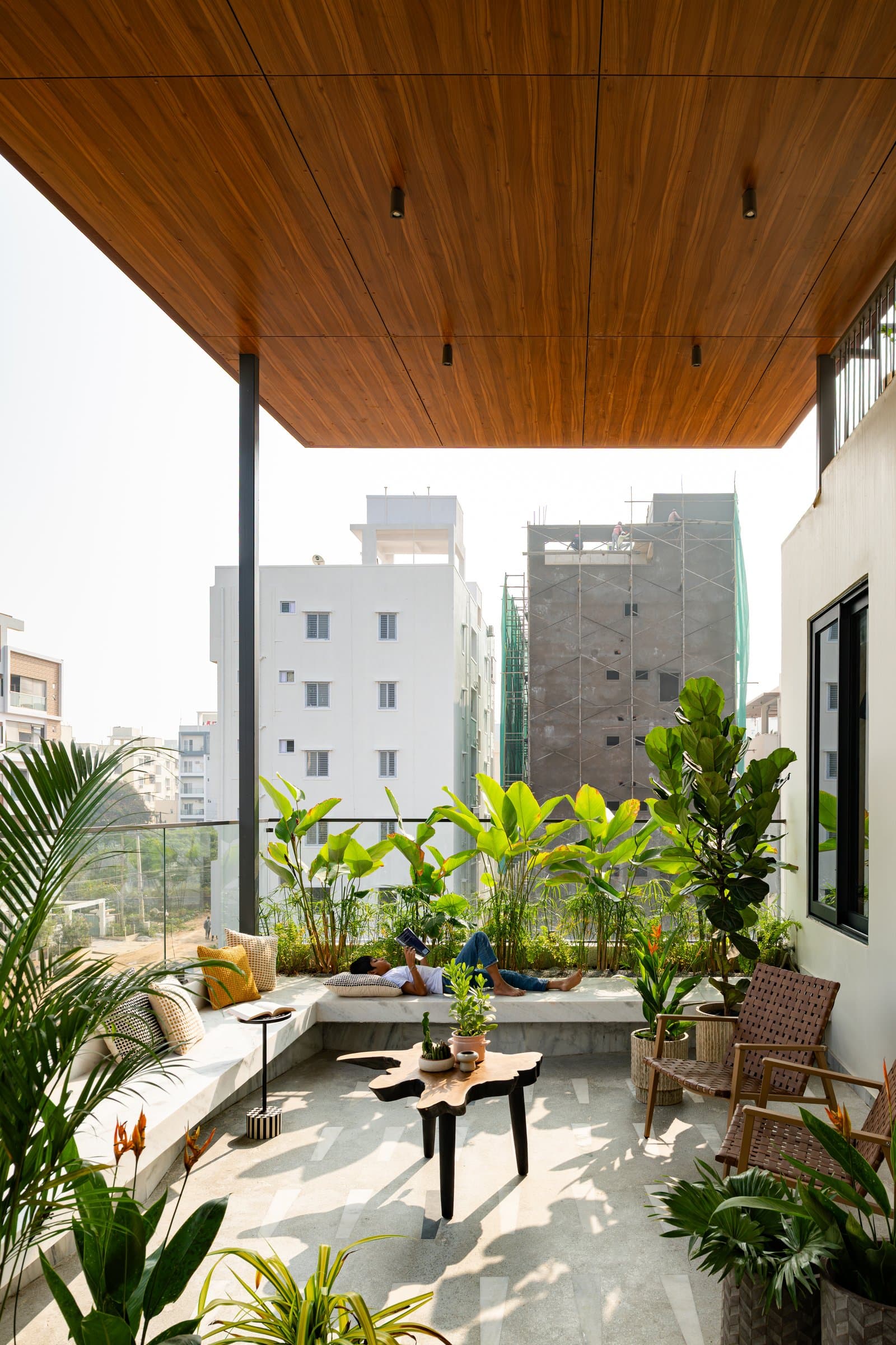 The upper terrace, where a deep teak soffit floats over a planted bench and stone floor