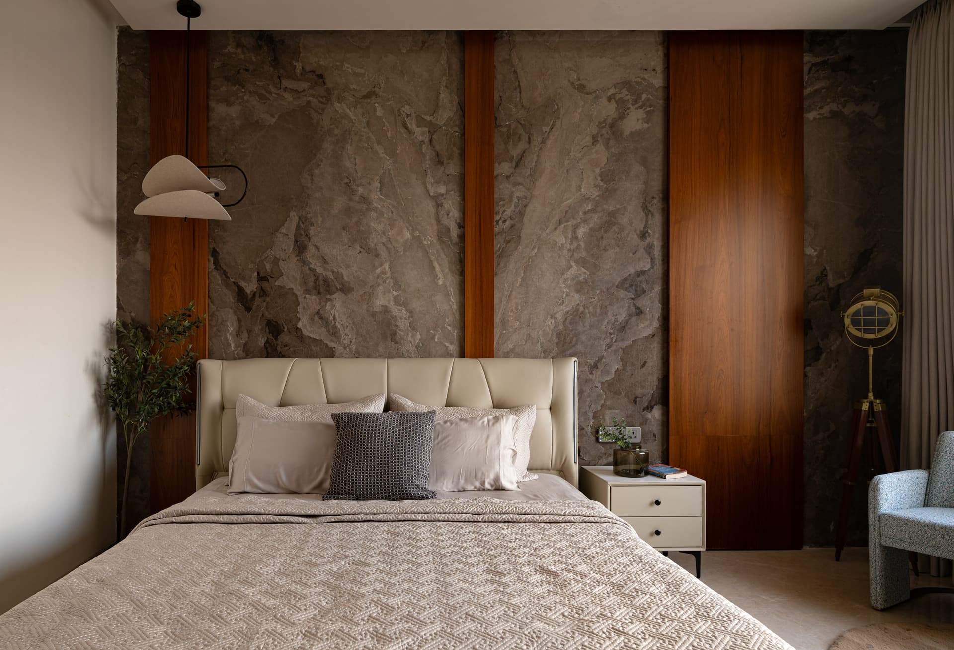 The master suite headboard wall: grey-veined stone divided by vertical teak inserts