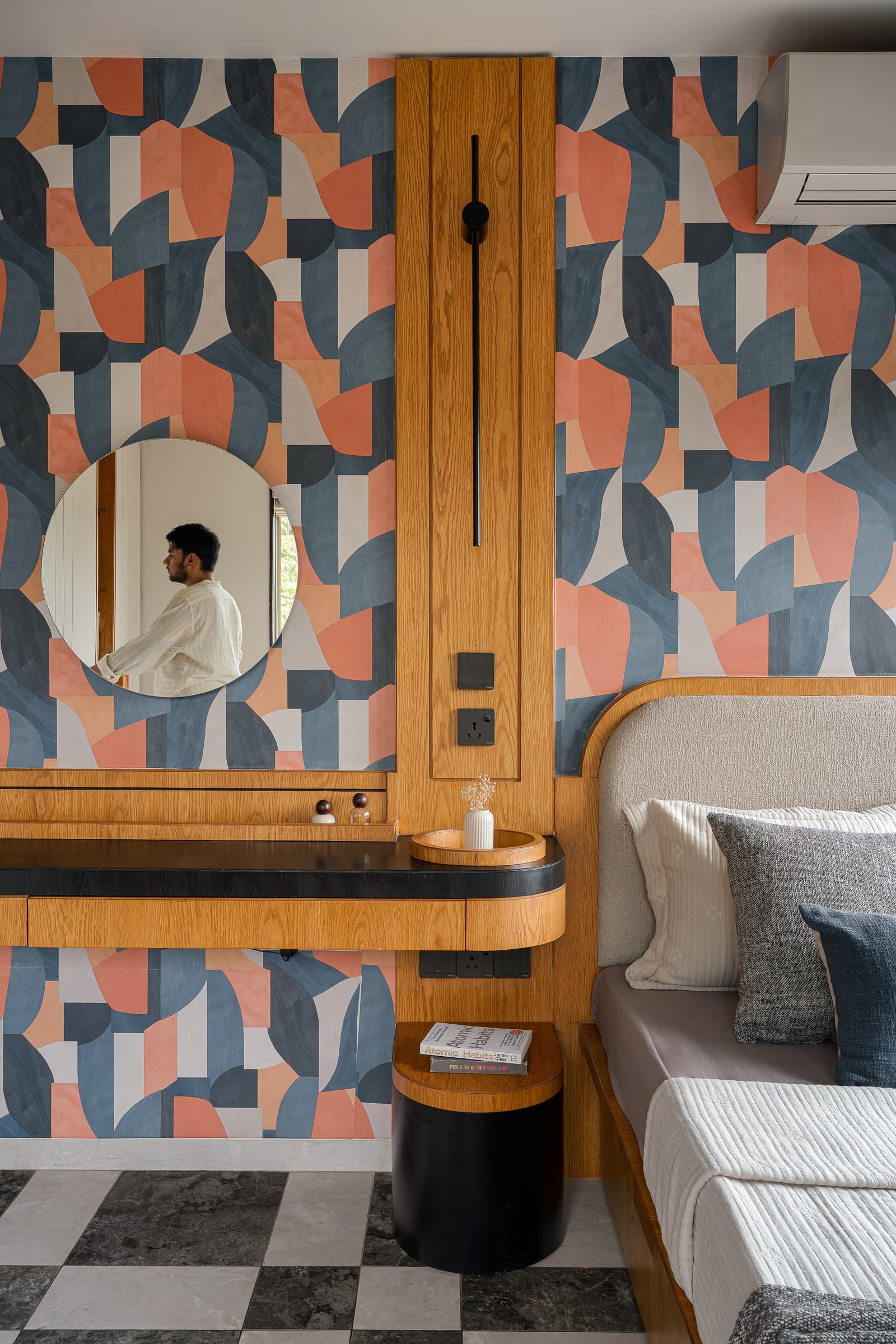 A graphic wallpaper behind the bed earns its boldness because everywhere else in the apartment has held its tongue