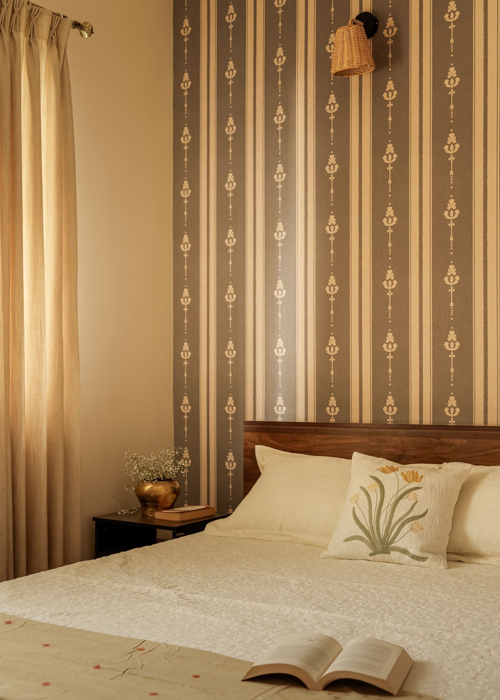 The guest bedroom, where a striped patterned wallpaper rises behind a low wooden headboard