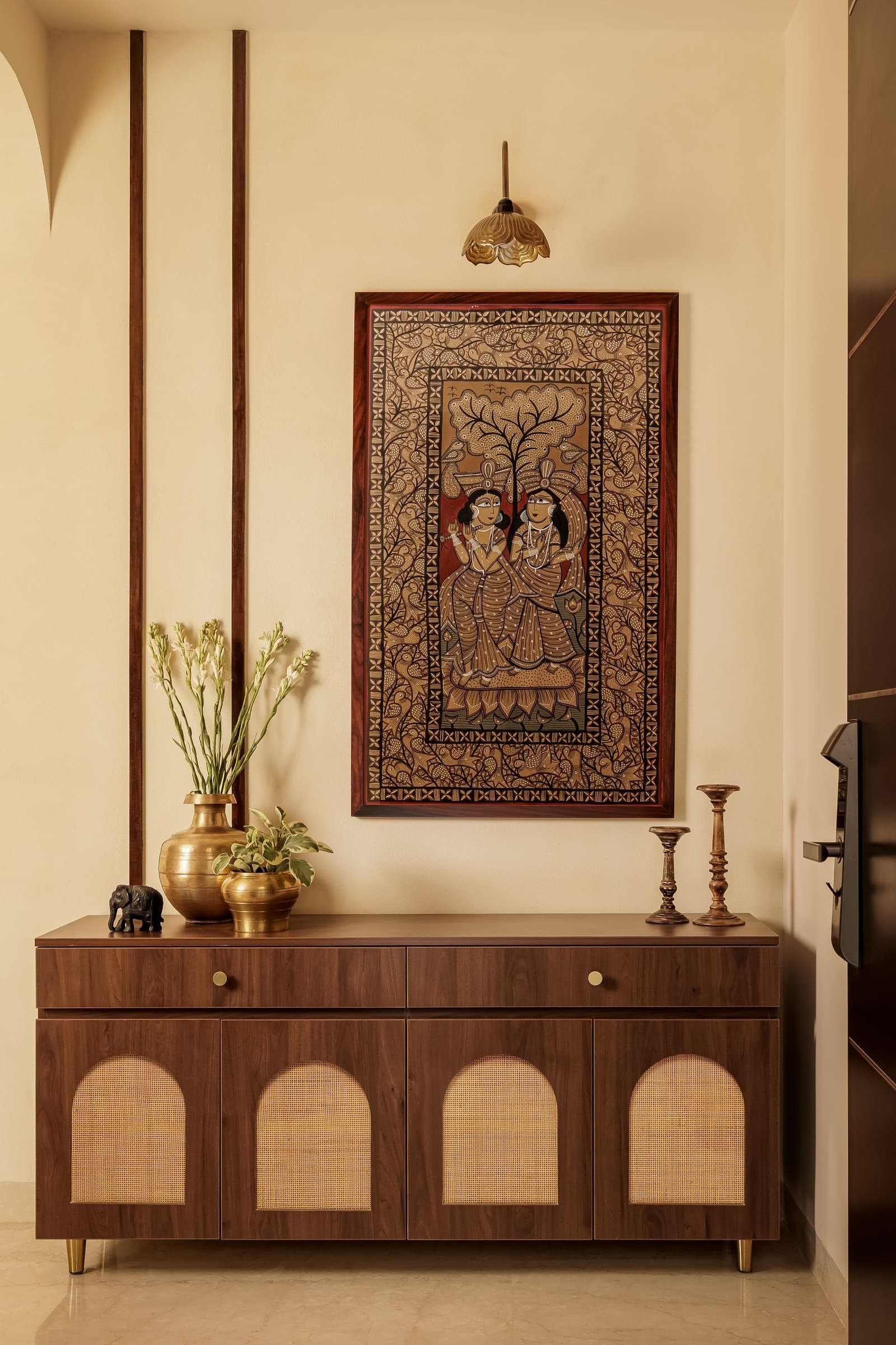 The console wall, its arched cane panels and twin vertical wooden strips distilling the home's grammar in a single piece of joinery
