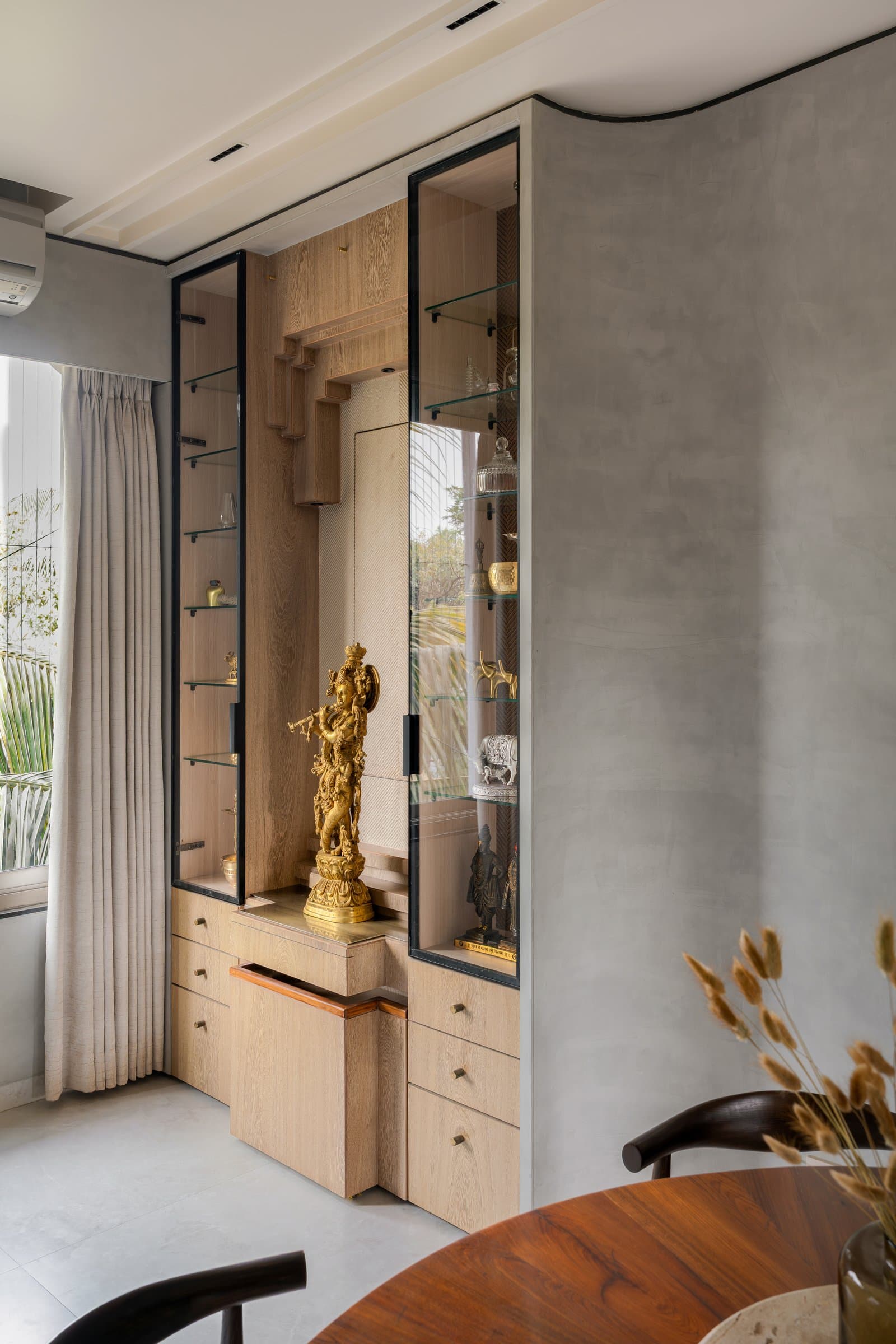 The devotional vitrine: given its own architectural moment within the dining wall, lit and proportioned like the room around it