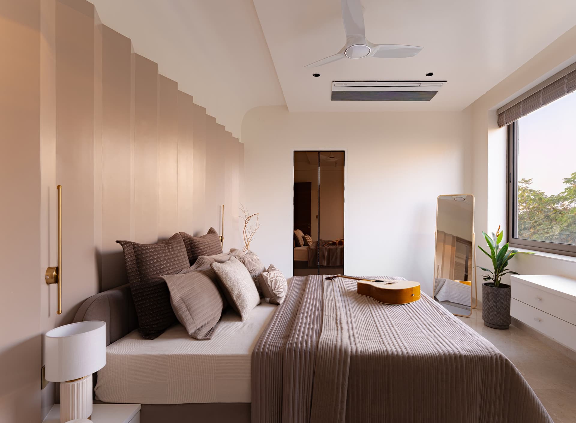The elder son's bedroom, enveloped by a fluted blush plaster wall under a softly sloping ceiling