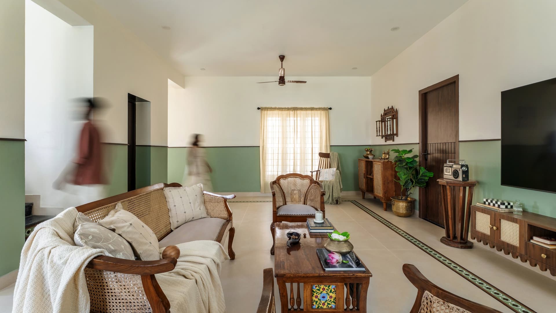 The living room pulled wider, with a sage dado wrapping the room and a patterned tile border tracing the floor's perimeter