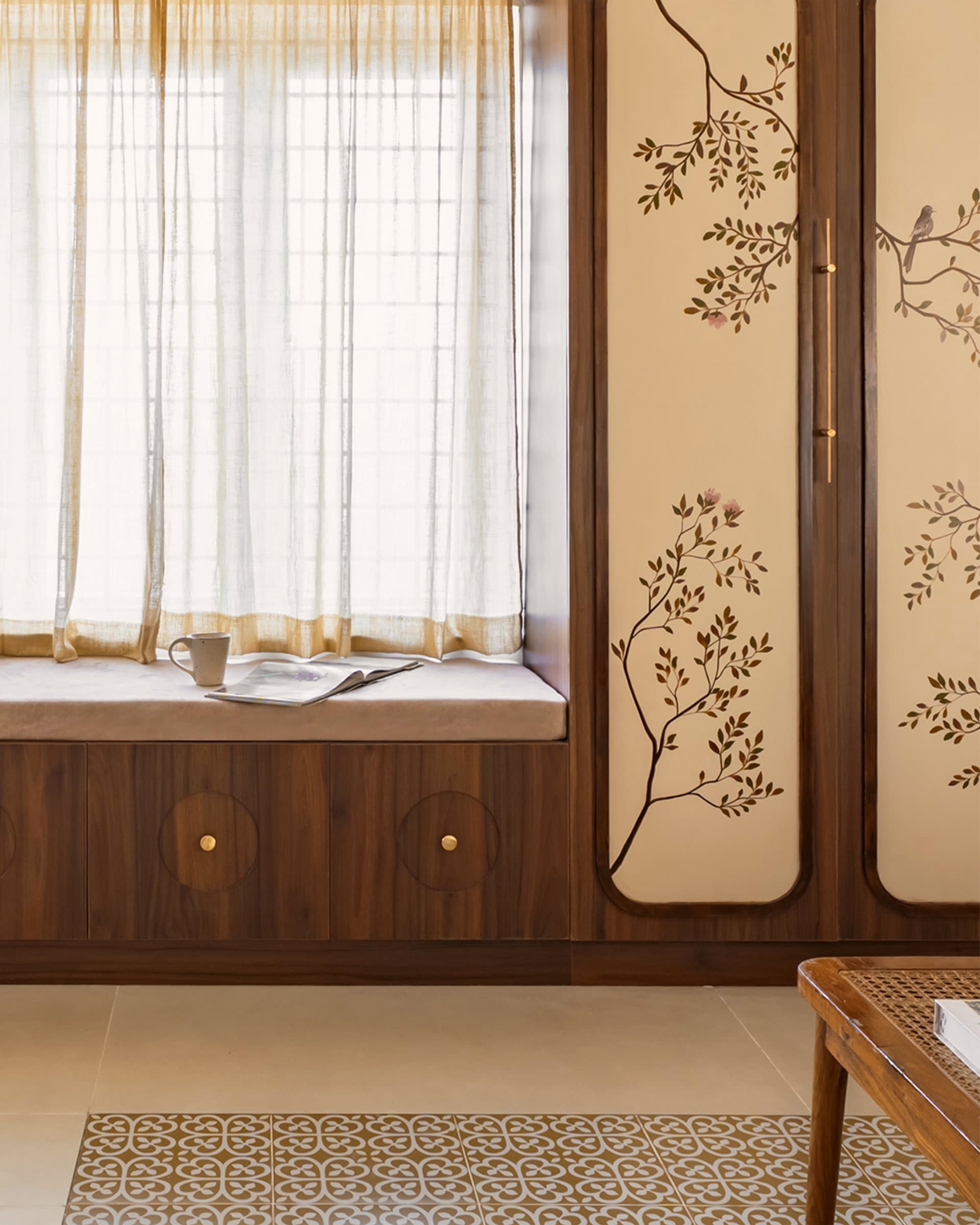 A built-in window seat tucked beside the wardrobe, finished with circular brass-pull medallions