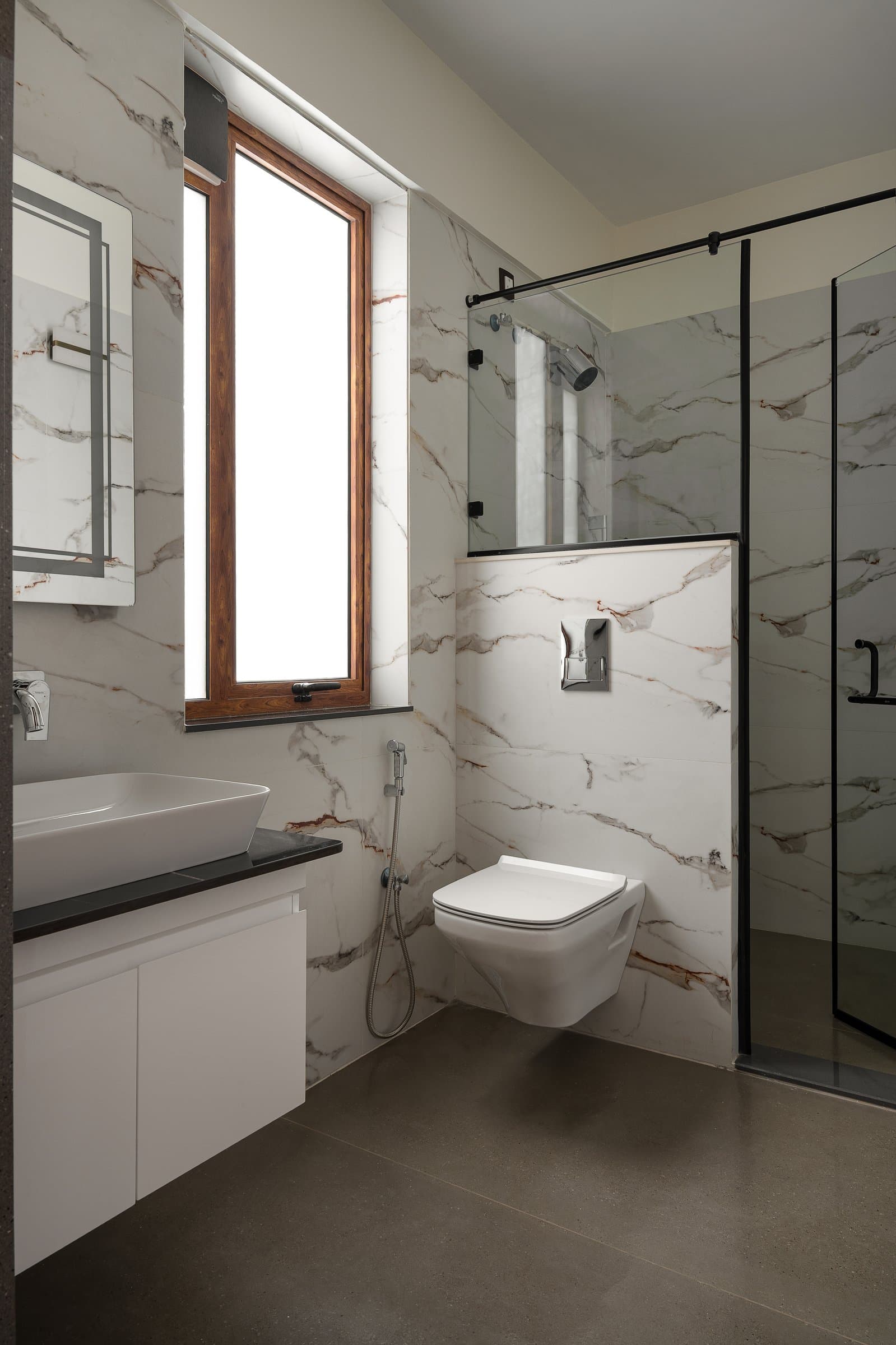 The first bathroom, in pale veined stone with a wood-framed window pulling daylight deep into the room