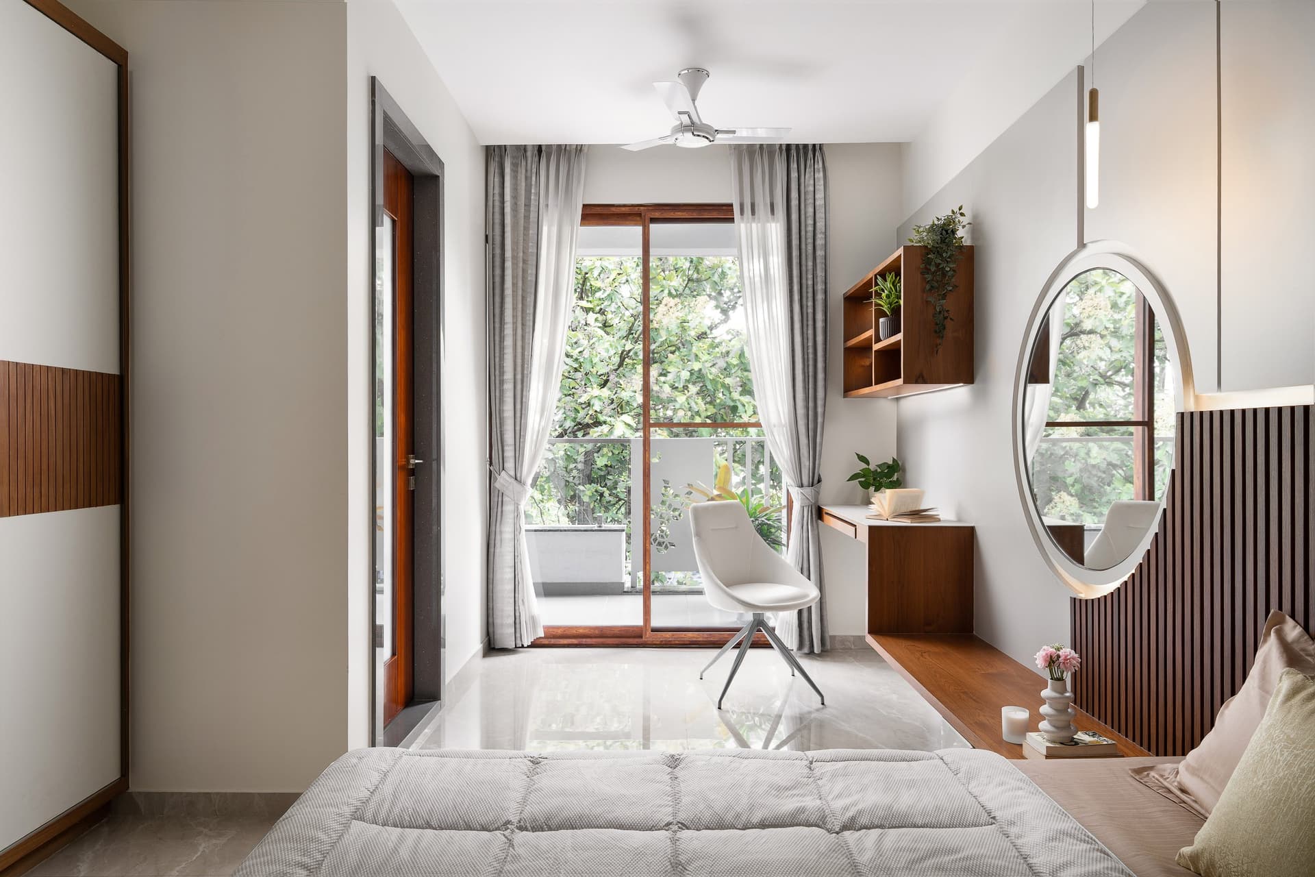 The smaller bedroom, organised around a haloed circular mirror set against a floor-to-ceiling fluted panel