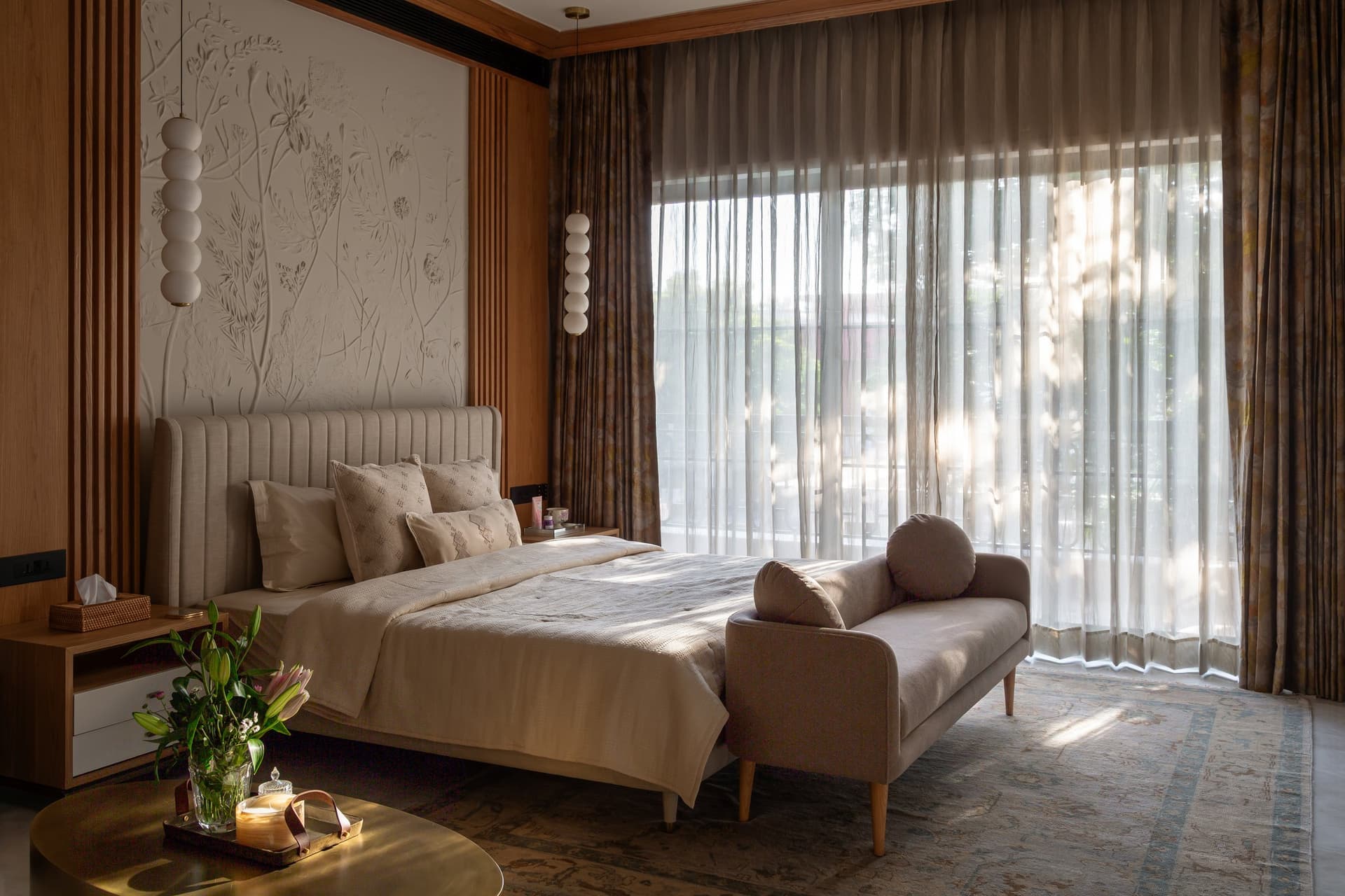The master bedroom, where a textured plaster botanical mural rises behind a channel-tufted bed in oat linen