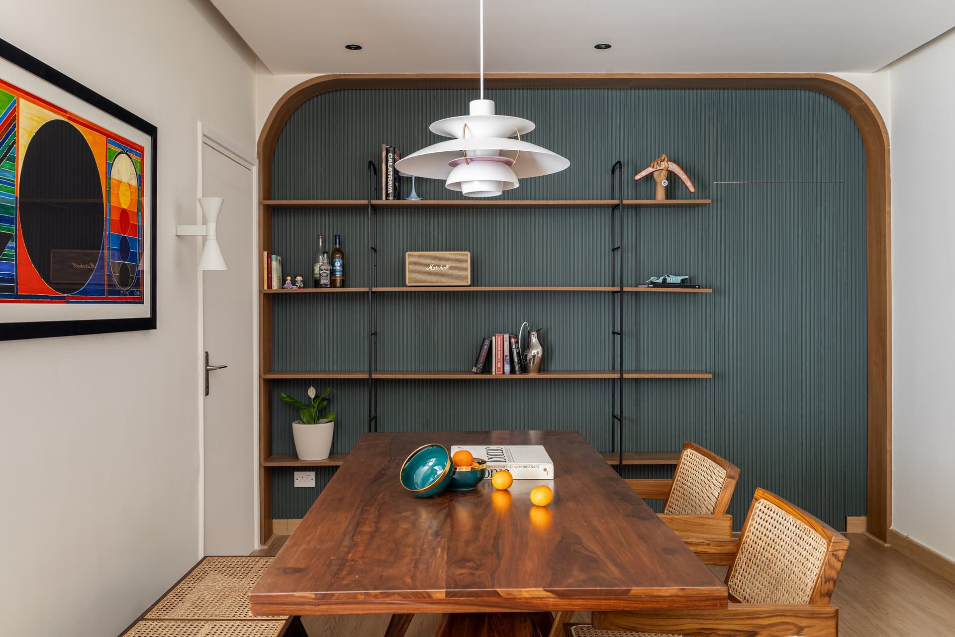 The dining wall, where a cantilever shelving system in wood and steel also conceals the door to the master bedroom