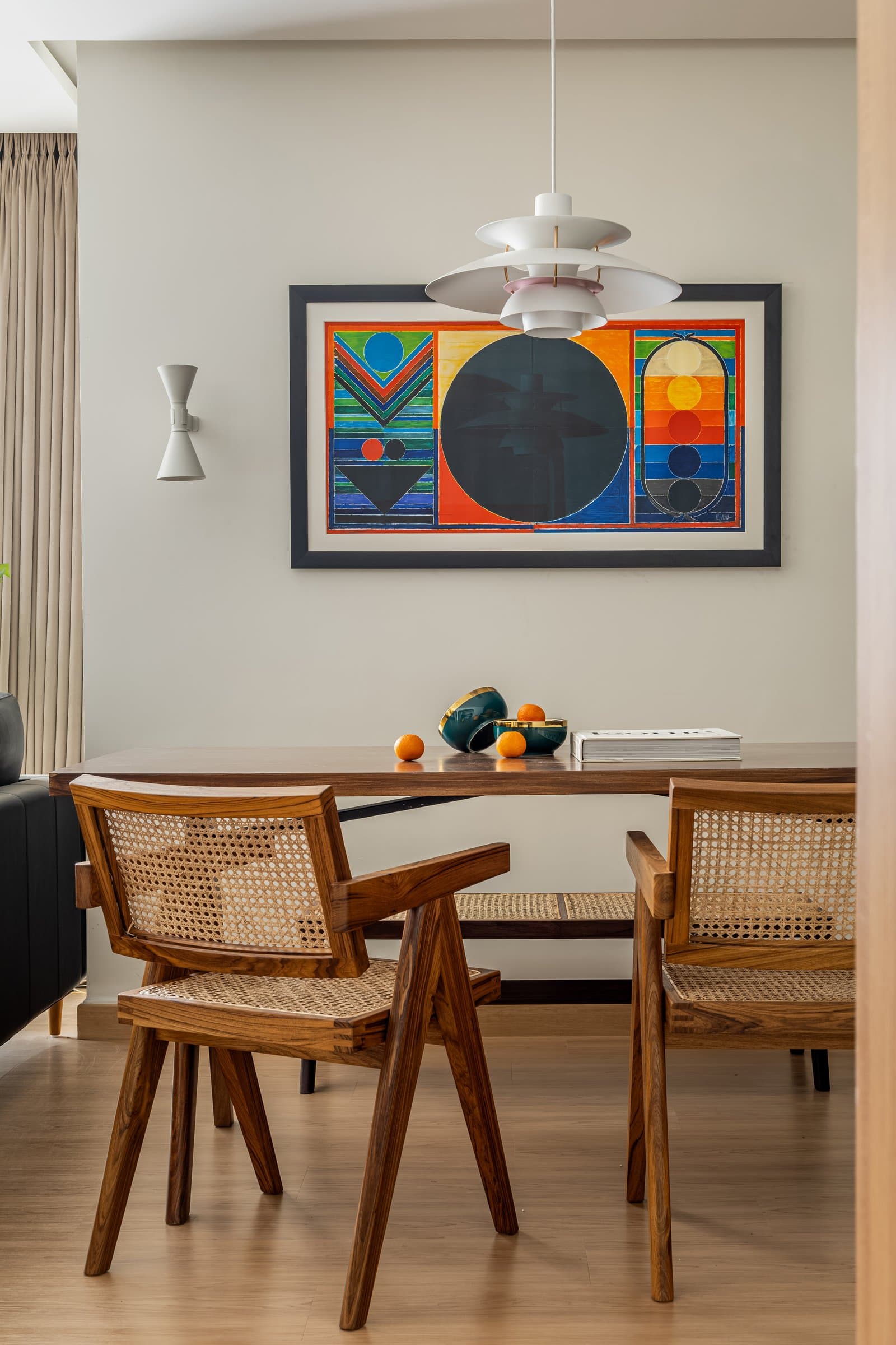 Chandigarh-style cane-and-teak chairs paired with the PH5 pendant: the home's most articulate cross-cultural pairing