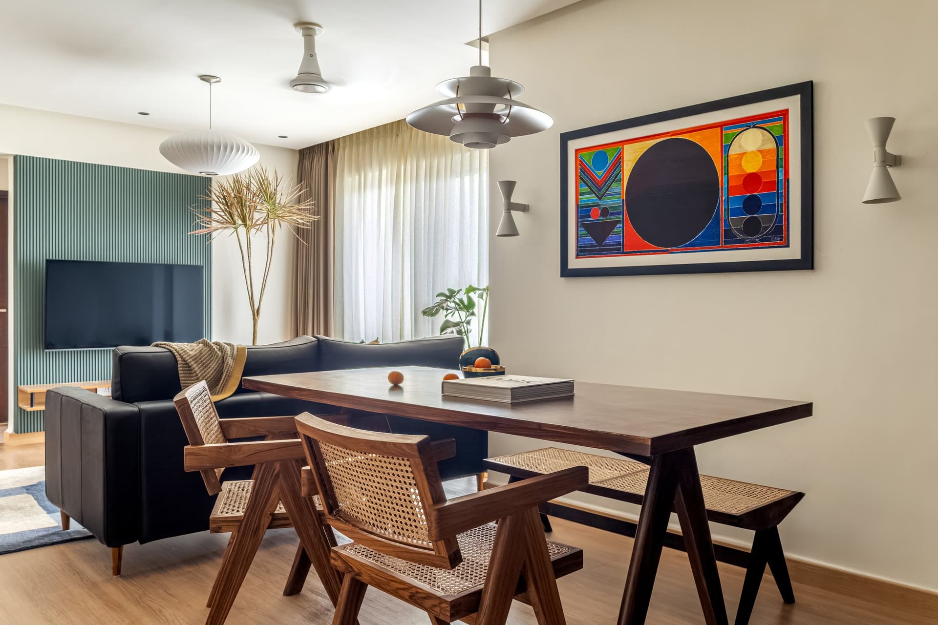 The living and dining volume opens as a single cohesive zone, anchored by the PH5 pendant and a Raza-style canvas