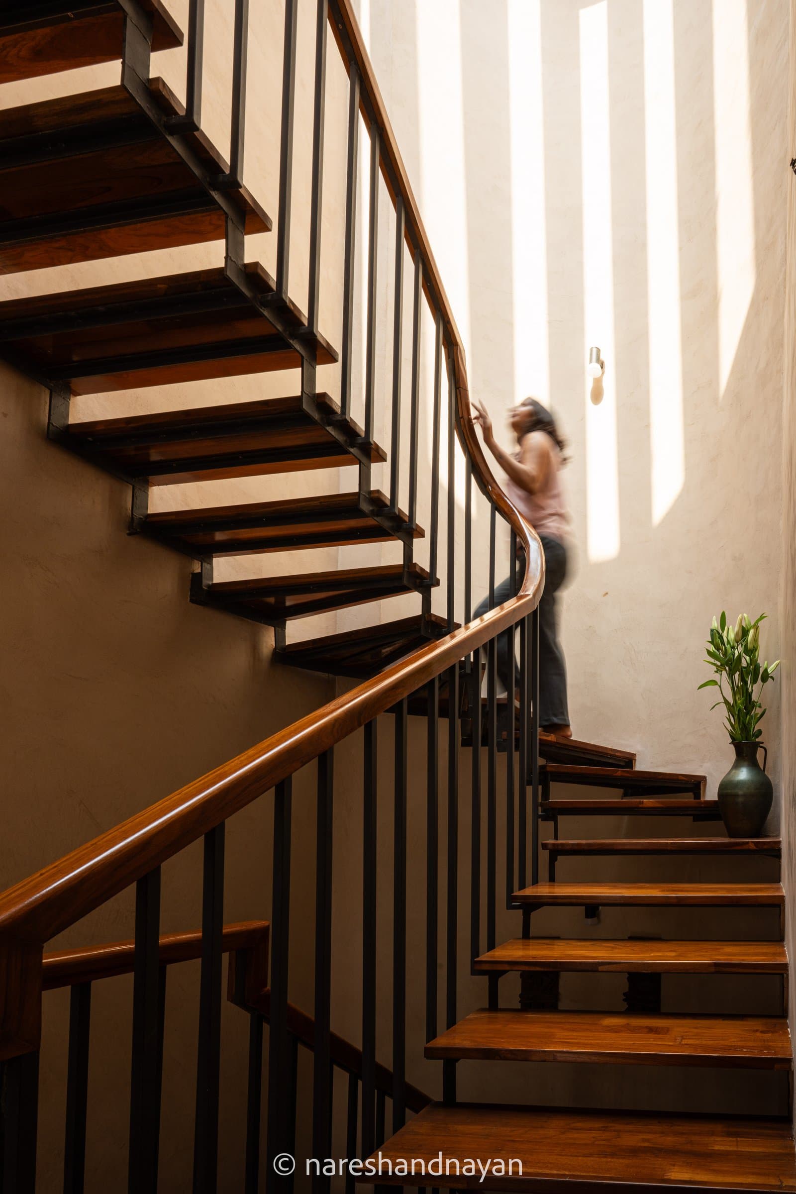 The central staircase, open hardwood treads on a slim metal stringer with a curved teak handrail