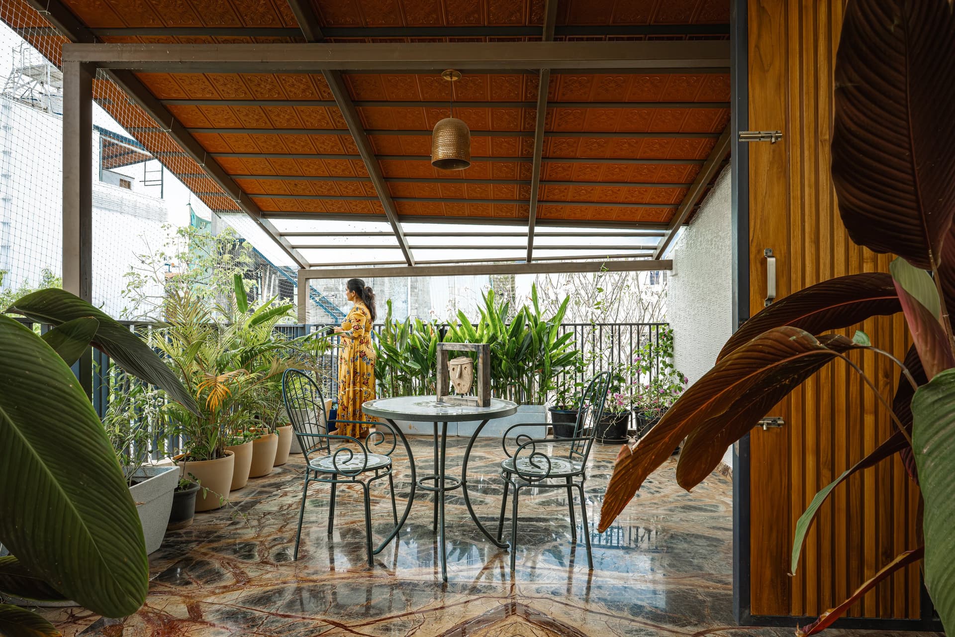 The terrace, treated as a third living room beneath a pressed-metal sheet ceiling