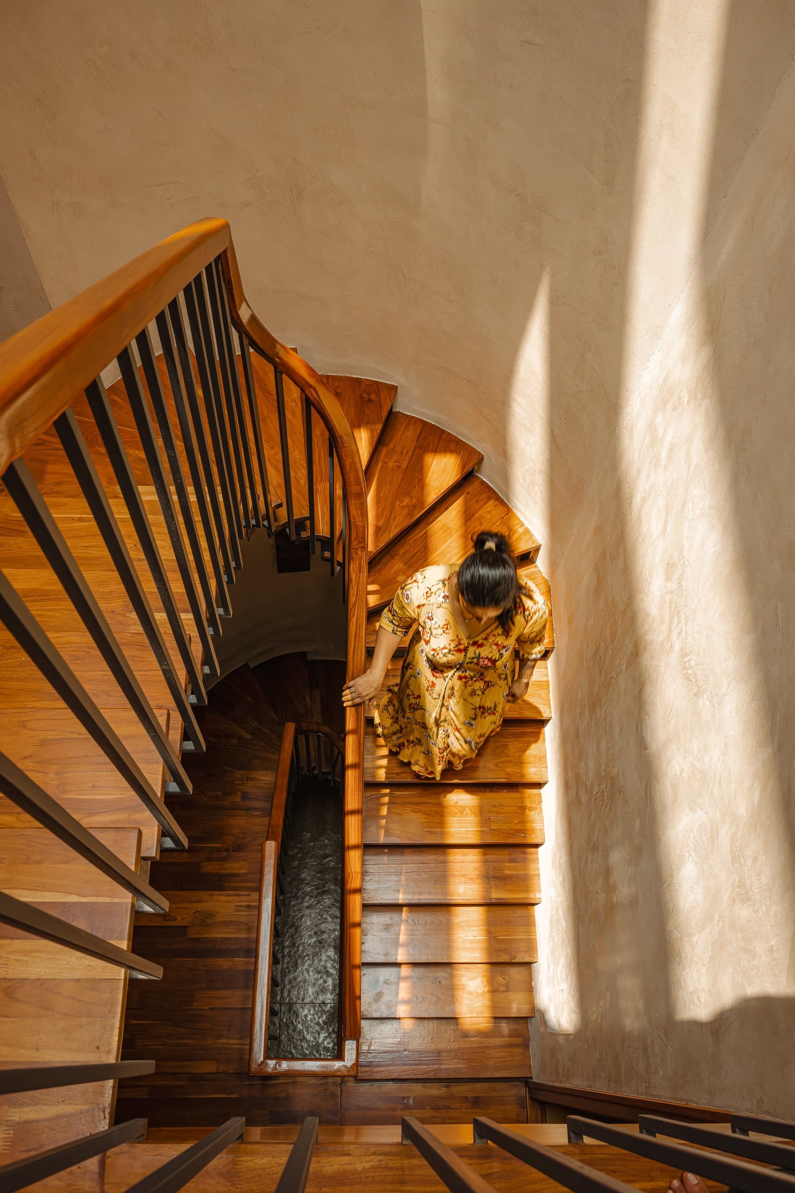 The stair seen from above, fanning around a tight pivot with lime-plastered walls wrapping the volume