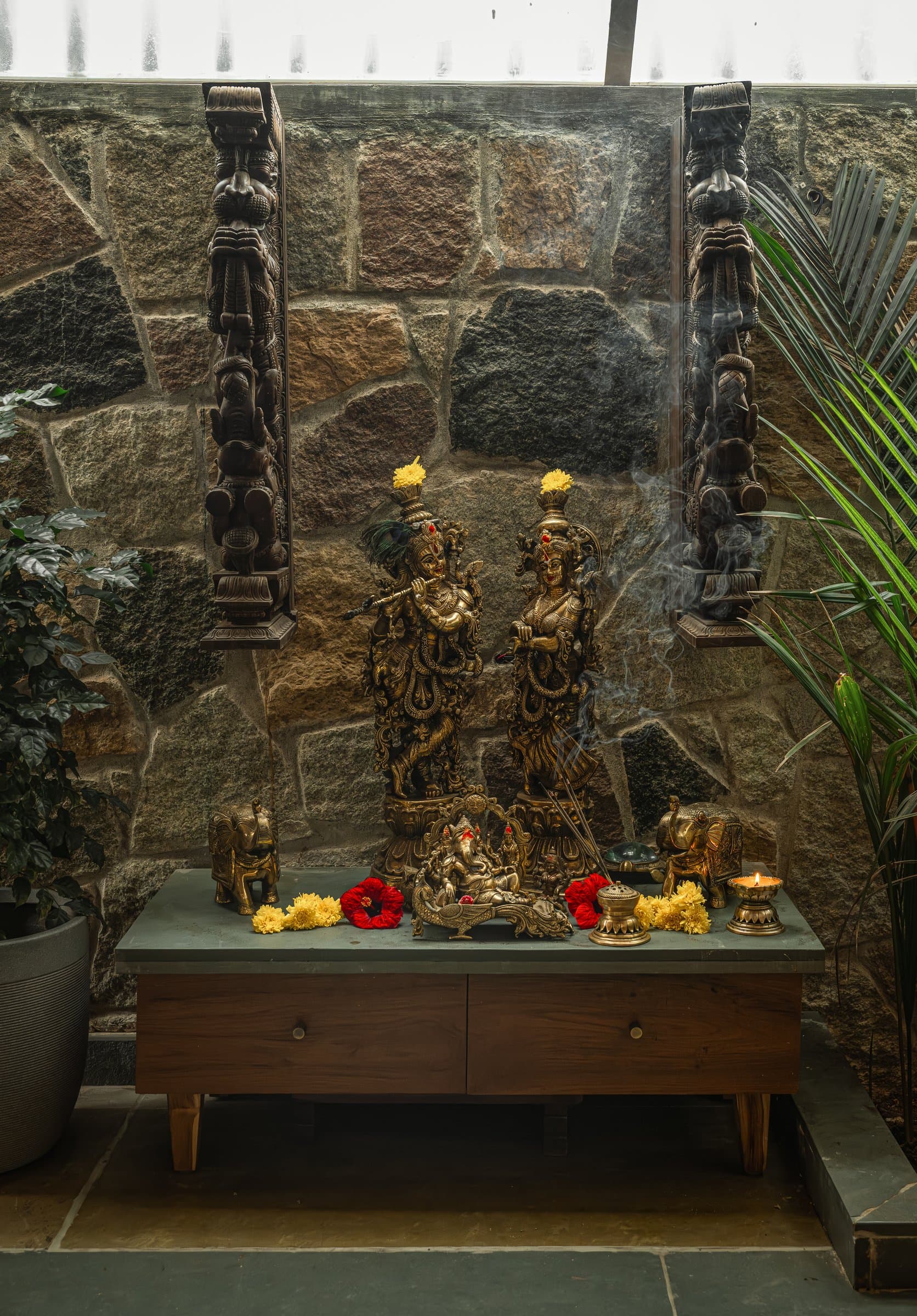 The puja, set on a low plinth against the rubble wall and flanked by two tall carved wooden brackets
