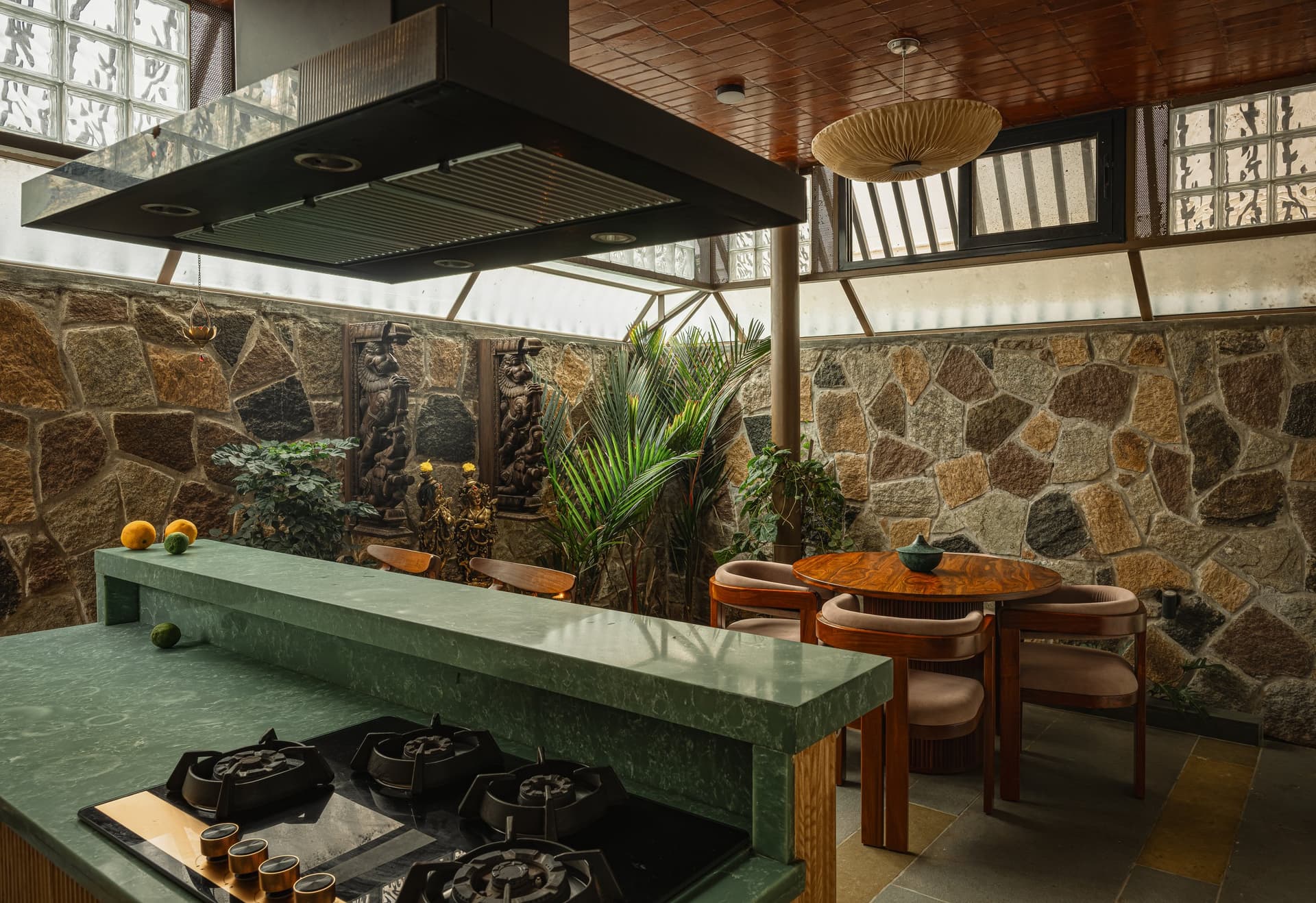 The kitchen-dining volume, where a long green stone counter, terracotta filler-slab ceiling and rubble wall hold the room together