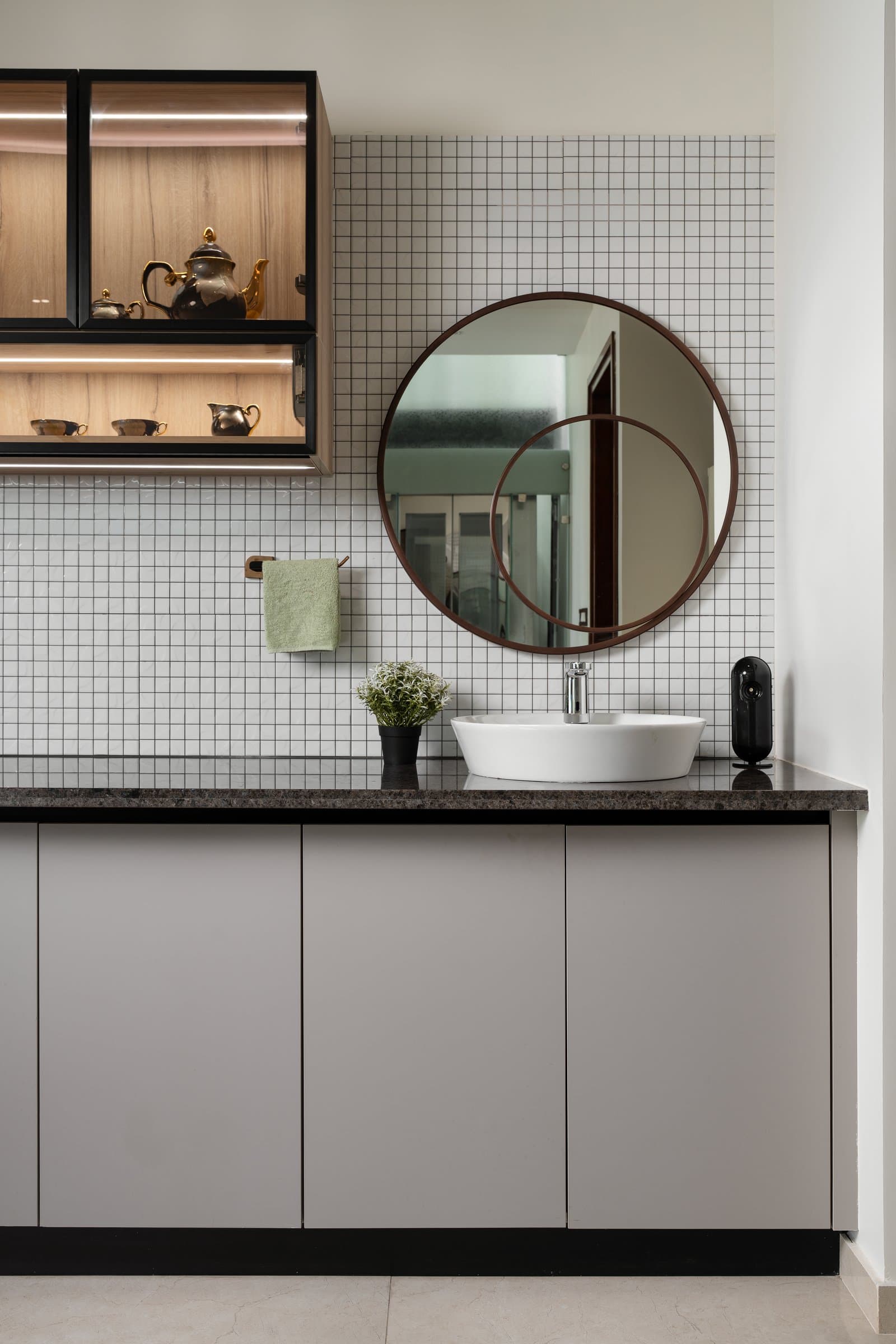 A wash counter beside the dining zone, where a wood-framed circular mirror completes a thought the tile has already begun