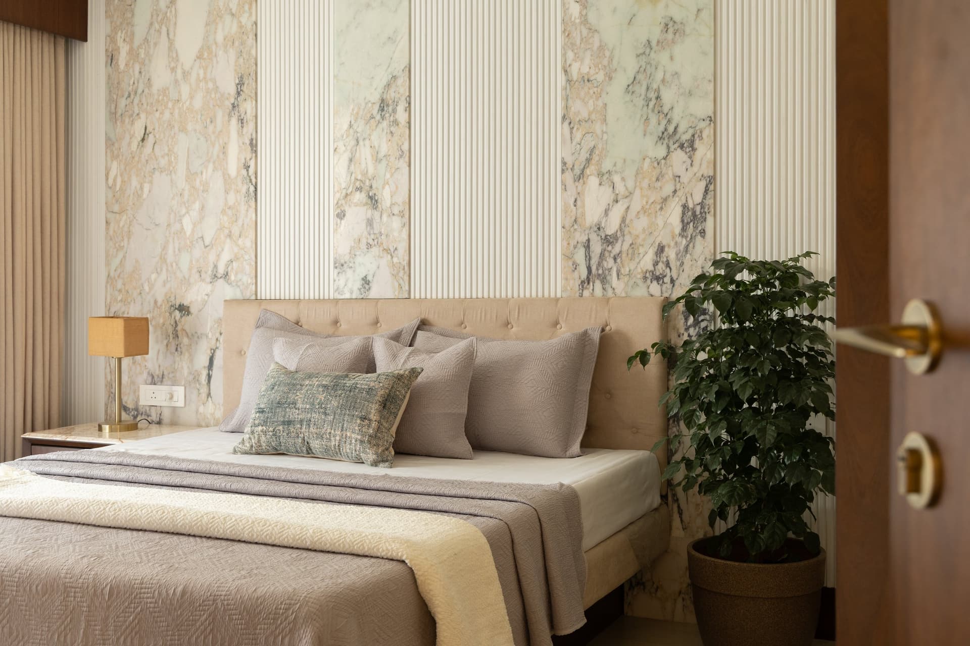 The second bedroom, its headboard wall composed in alternating panels of veined marble and fluted plaster