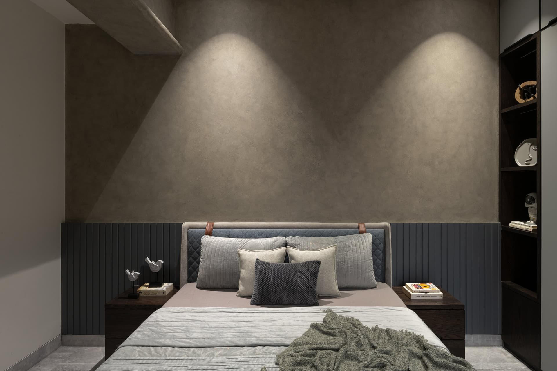 The son's bedroom commits to an exposed-materials thought: textured grey plaster washed by two cones of light