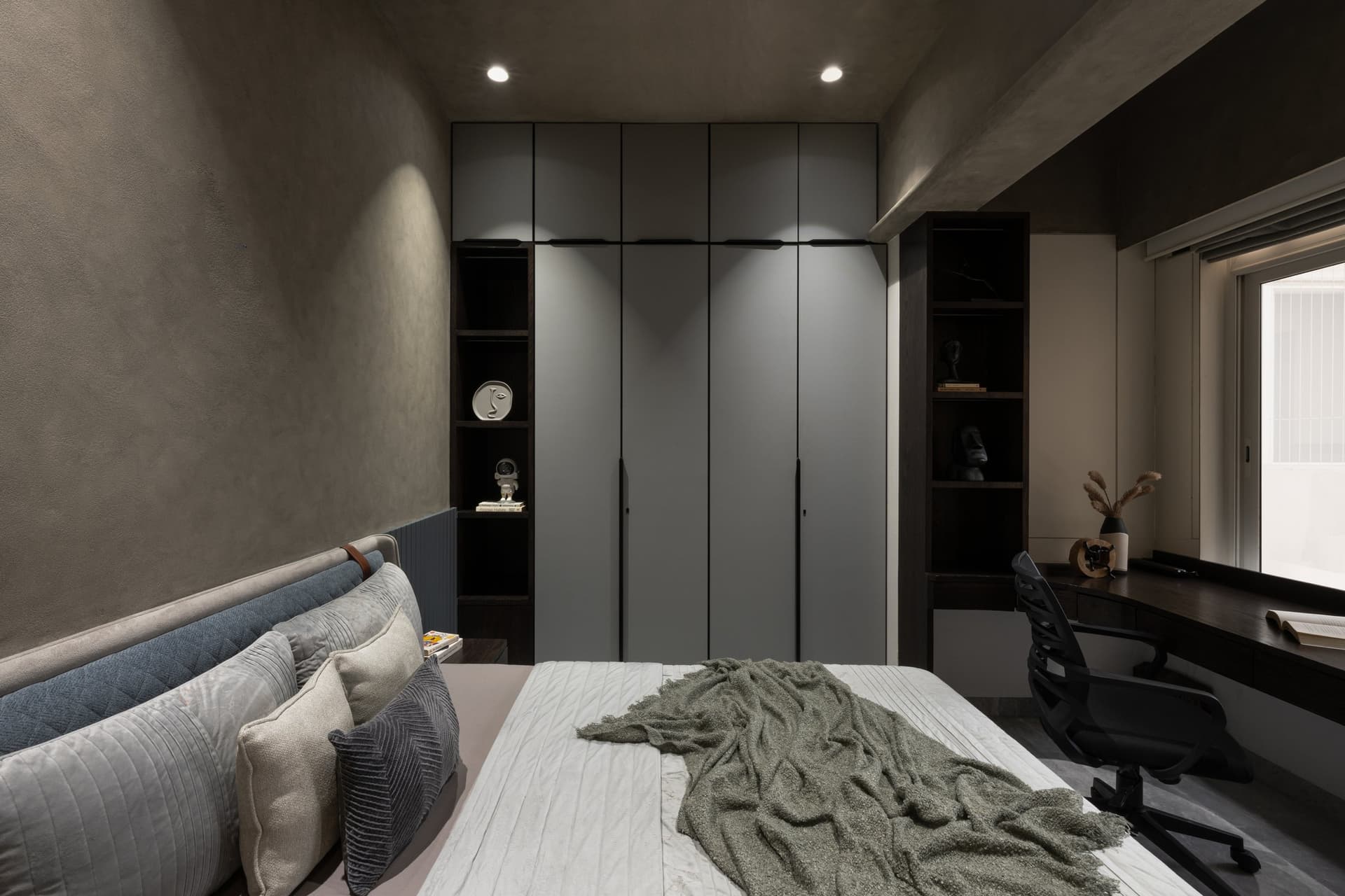The wider view: grey wardrobes flanked by deep-walnut open shelving and a window-side desk
