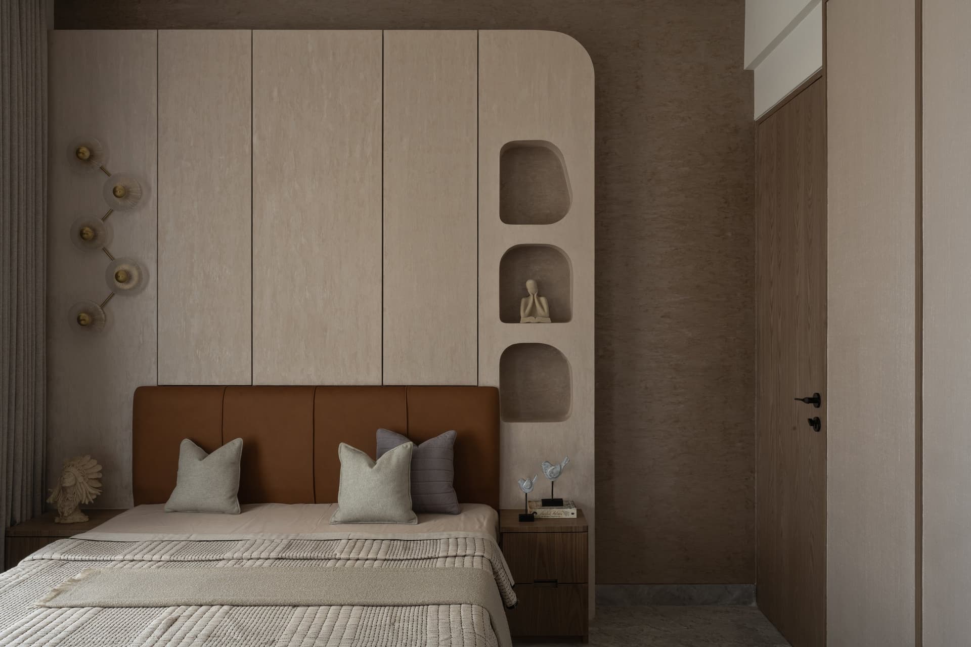The master bedroom, cocooned in monotone earth shades, terminates in a column of arched niches