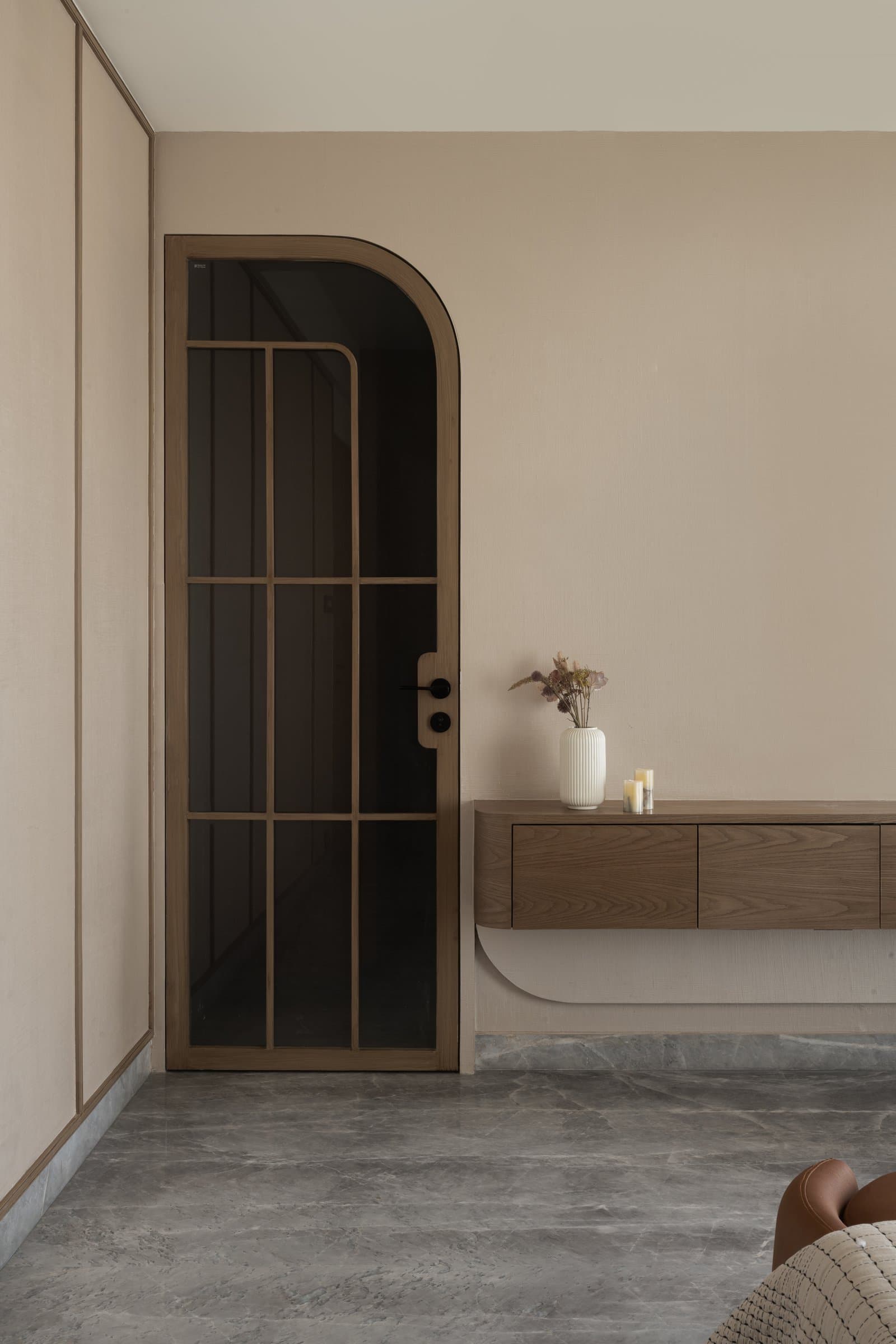 The corridor to the private wing: an arched glazed door and a floating walnut console with a curved underside