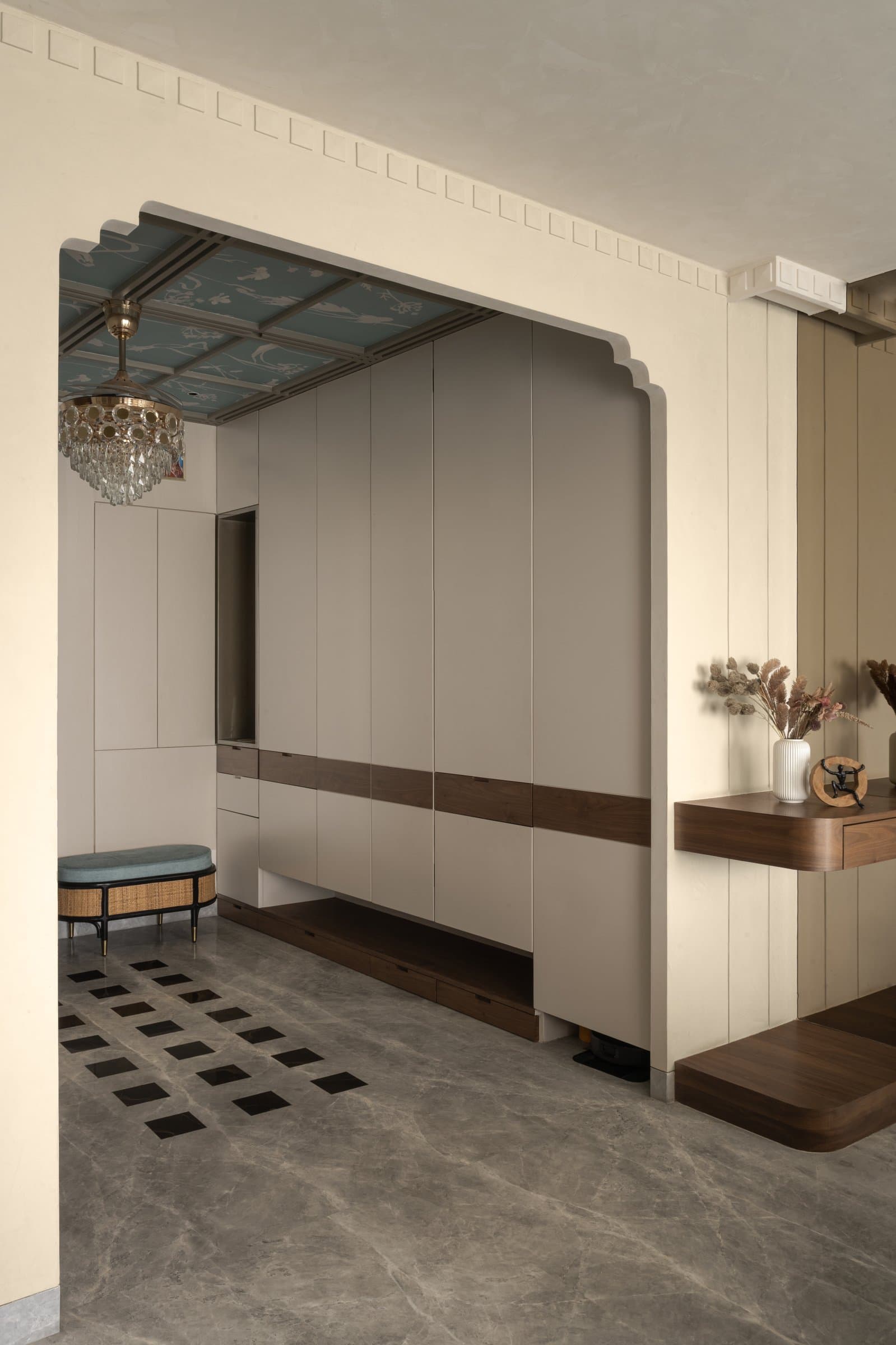 The foyer's scalloped portal frames concealed storage; the patterned marble floor draws the eye inward