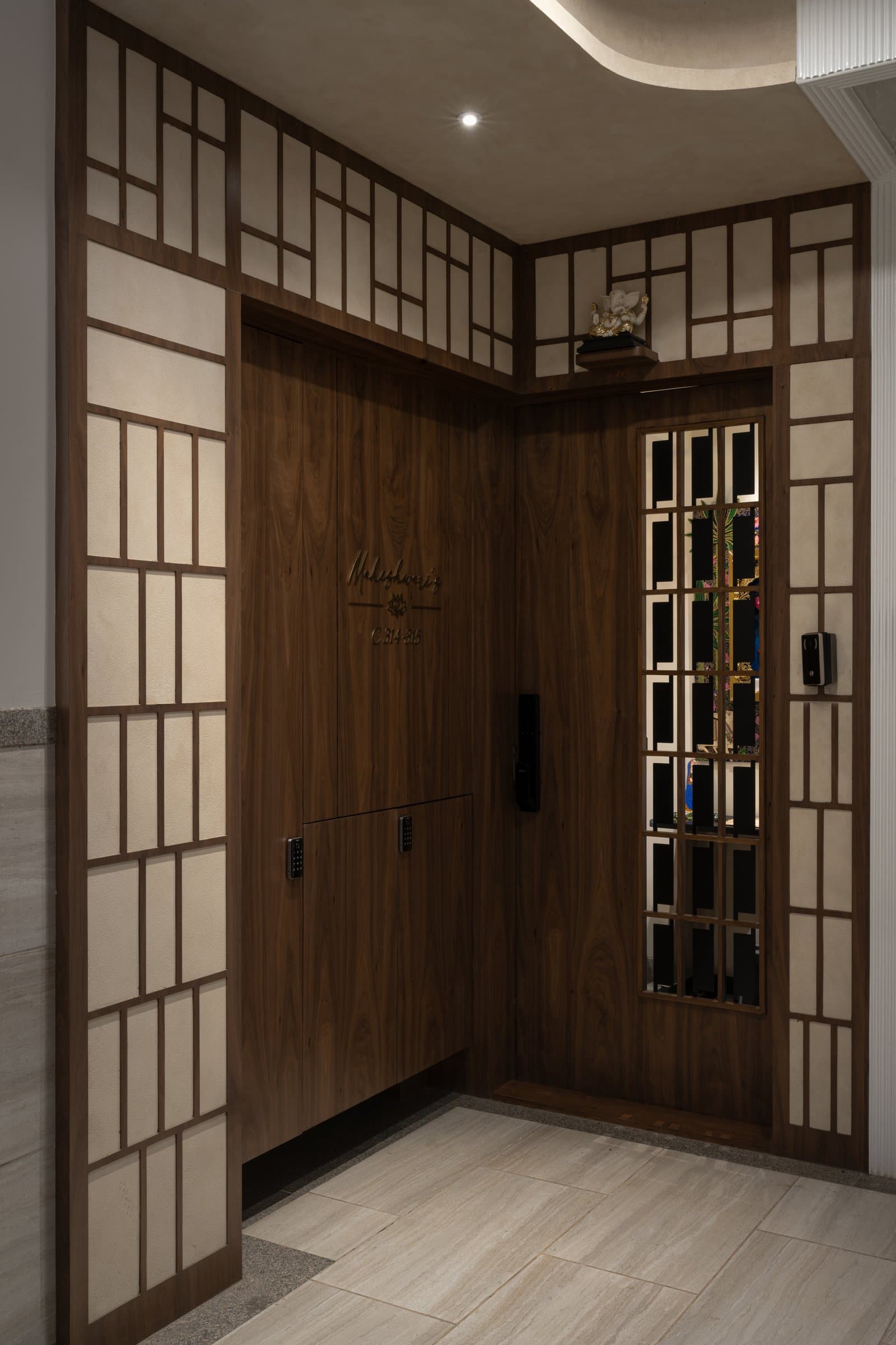 The entry threshold: a walnut-panelled door inset with fabric panels and a glimpse of the temple within