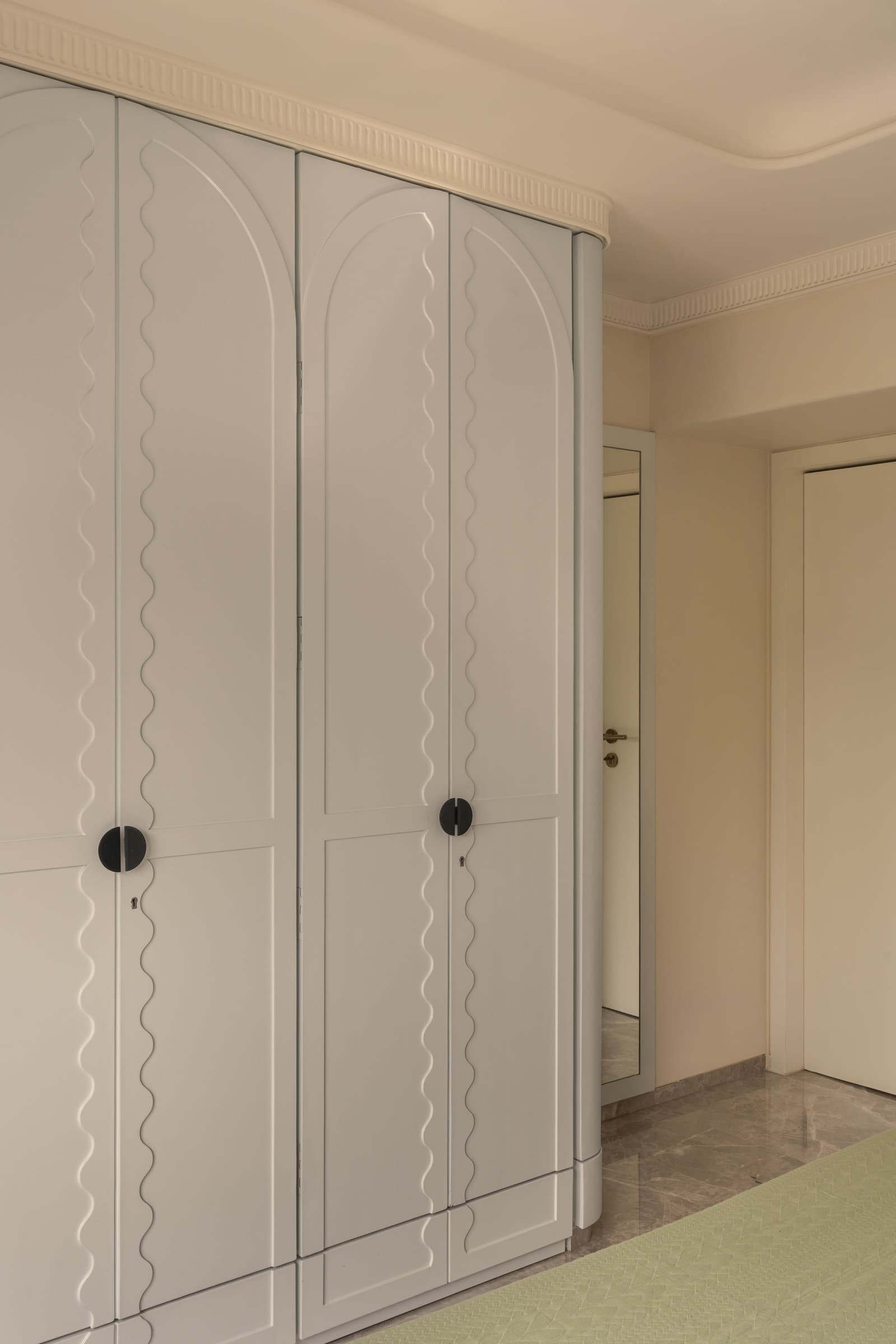 The second bedroom, where a grid of marbled cream panels frames a mustard velvet headboard