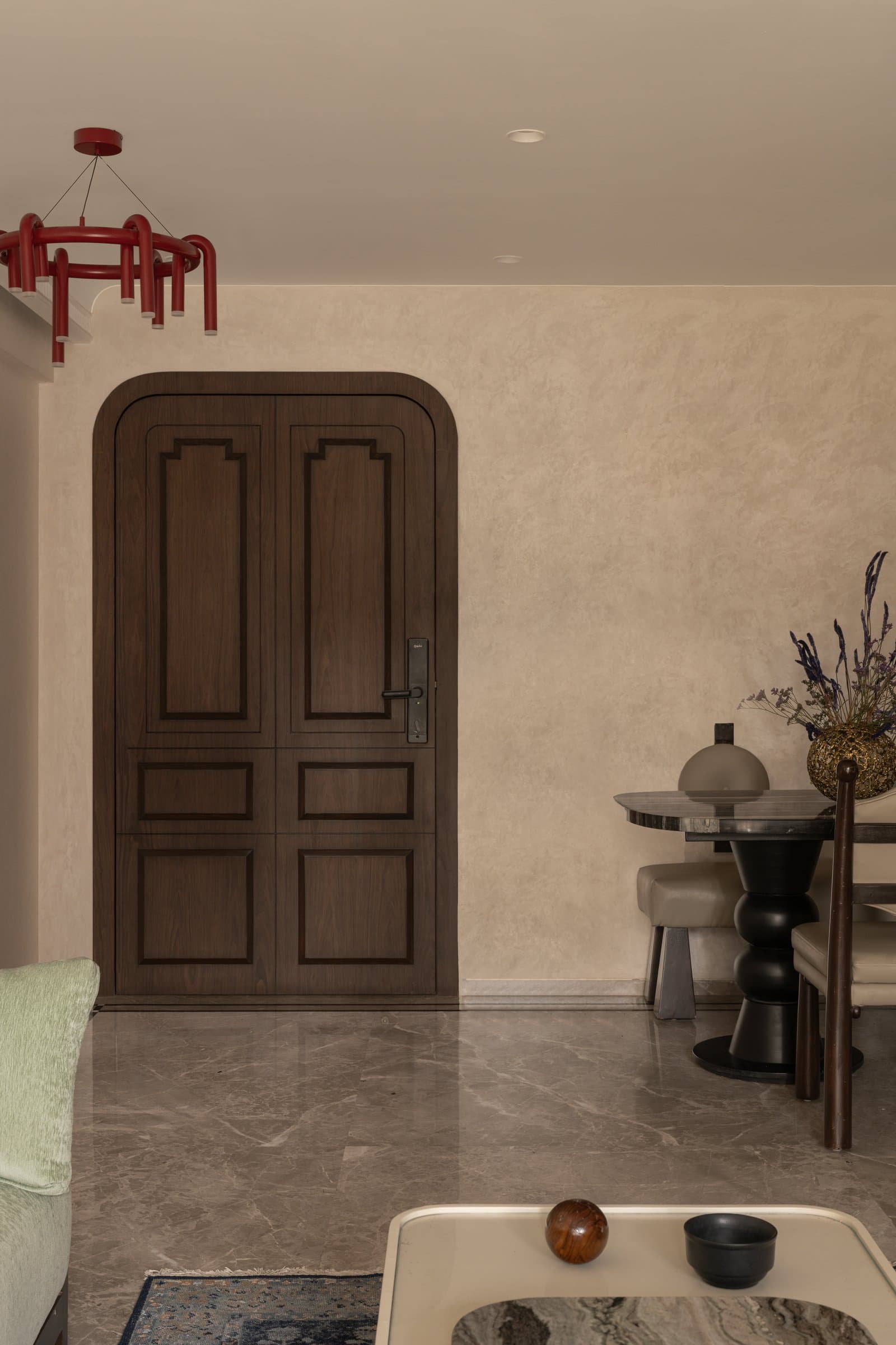 The entry door in panelled walnut against a softly plastered wall, with the dining edge visible alongside