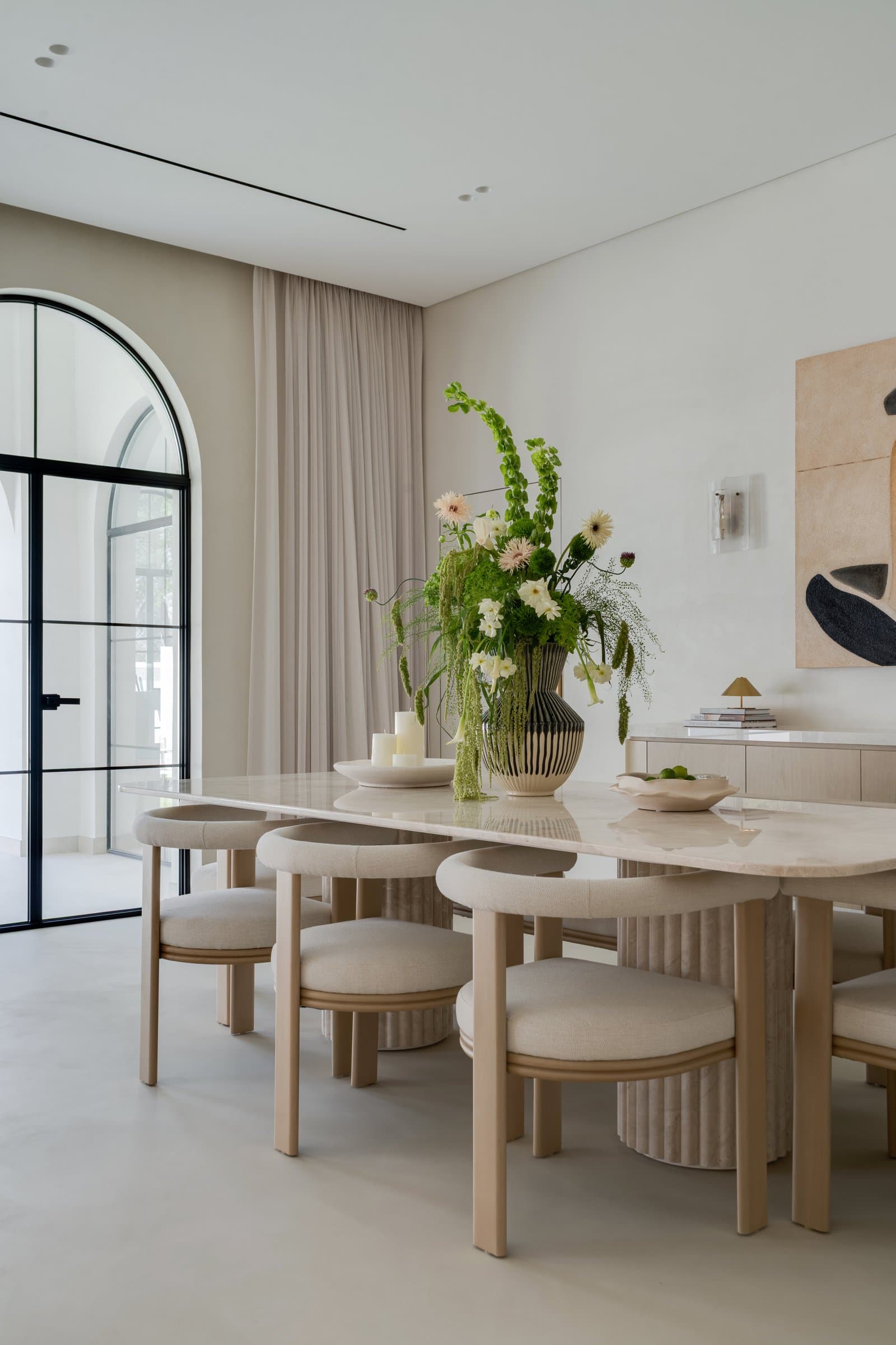 A second arched Crittall door opens the dining room onto the garden, framed by linen drapes