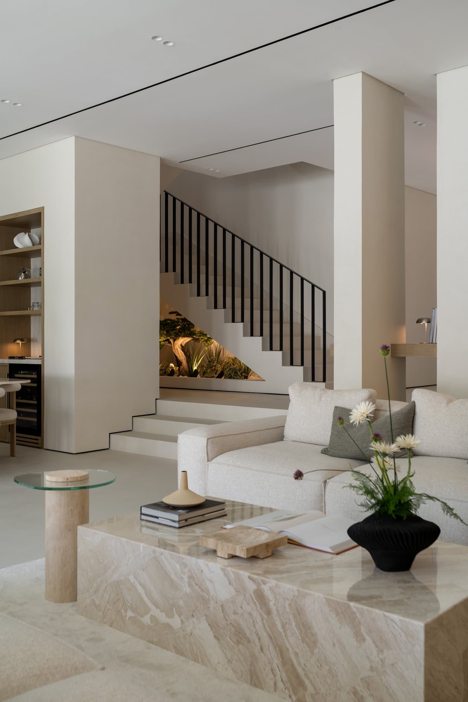 The indoor garden beneath the staircase glows softly under integrated lighting