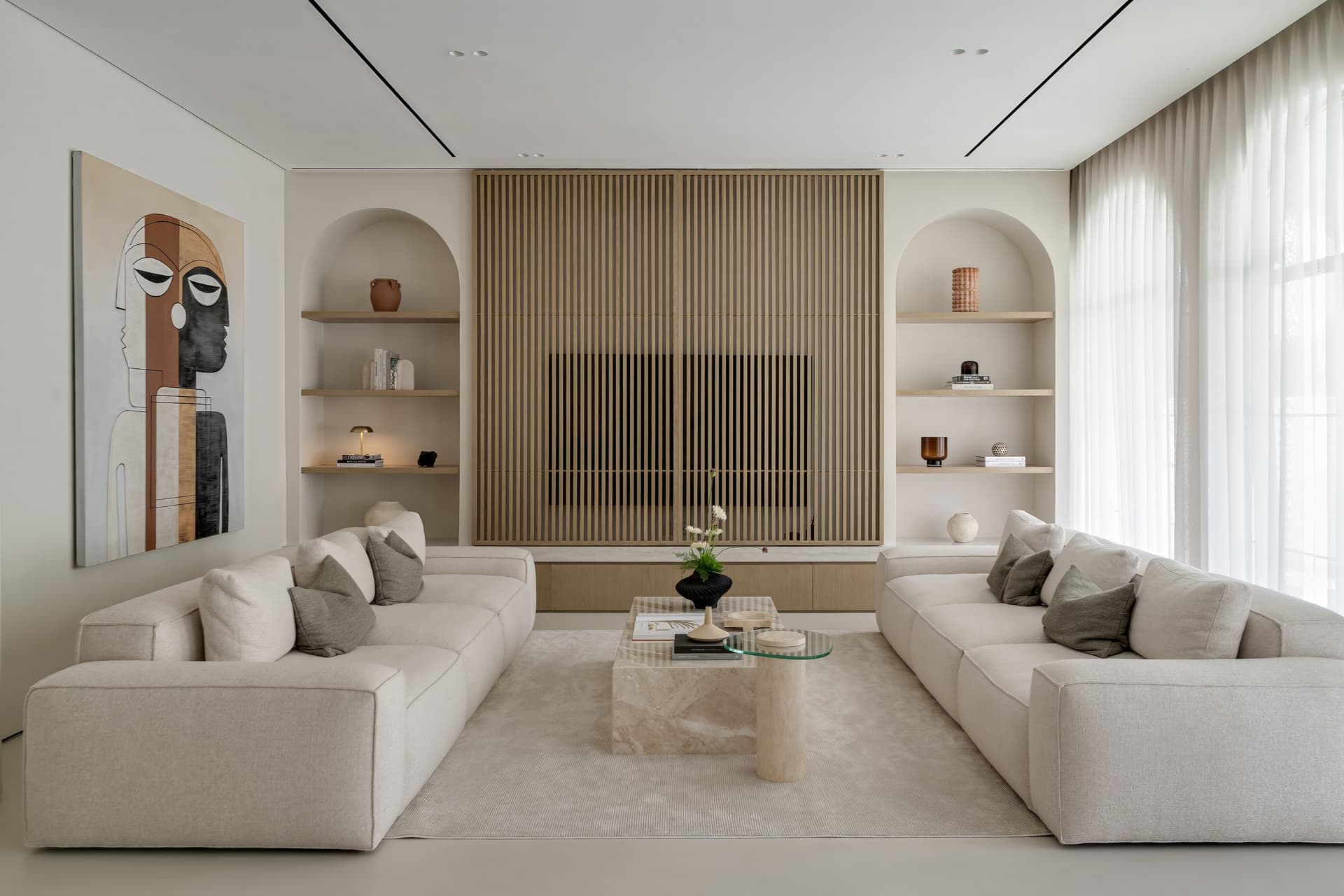 The living room, where a slatted oak wall conceals the television and arched niches echo the façade's openings