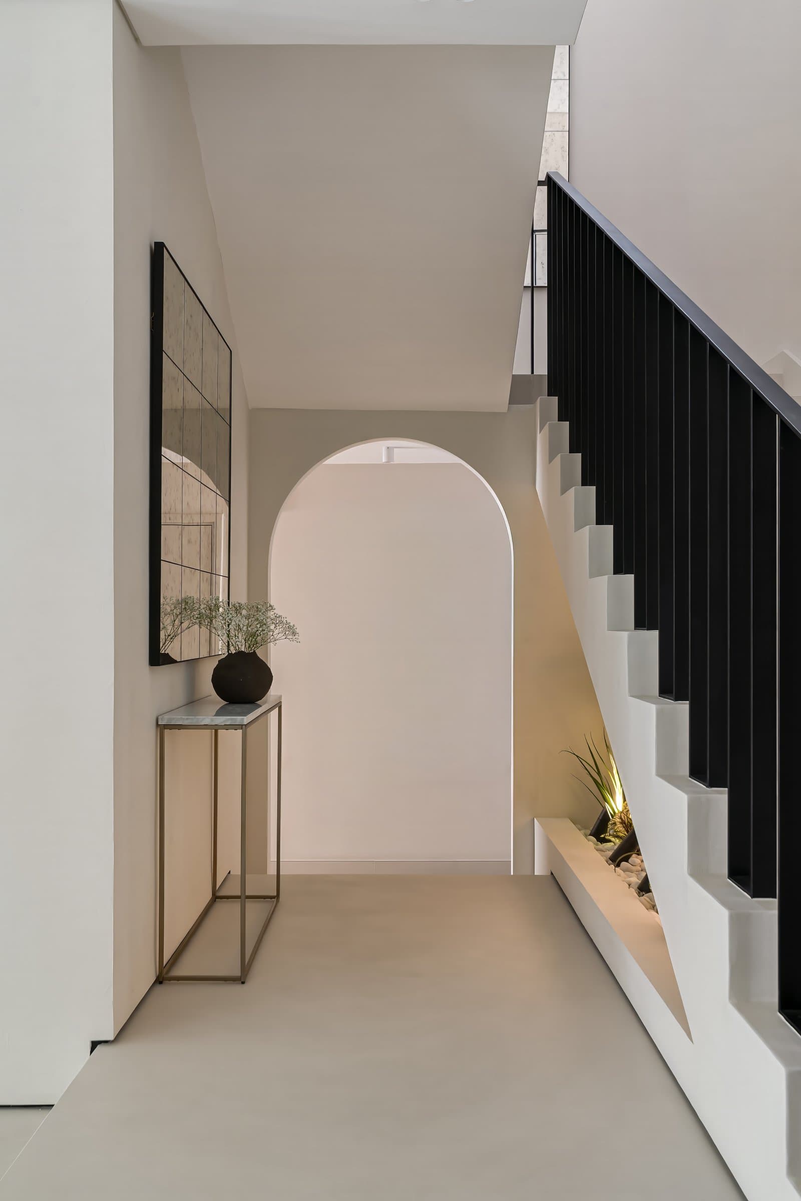 The entry hall, where micro-cement surfaces and an arched threshold introduce the home's continuous architectural language