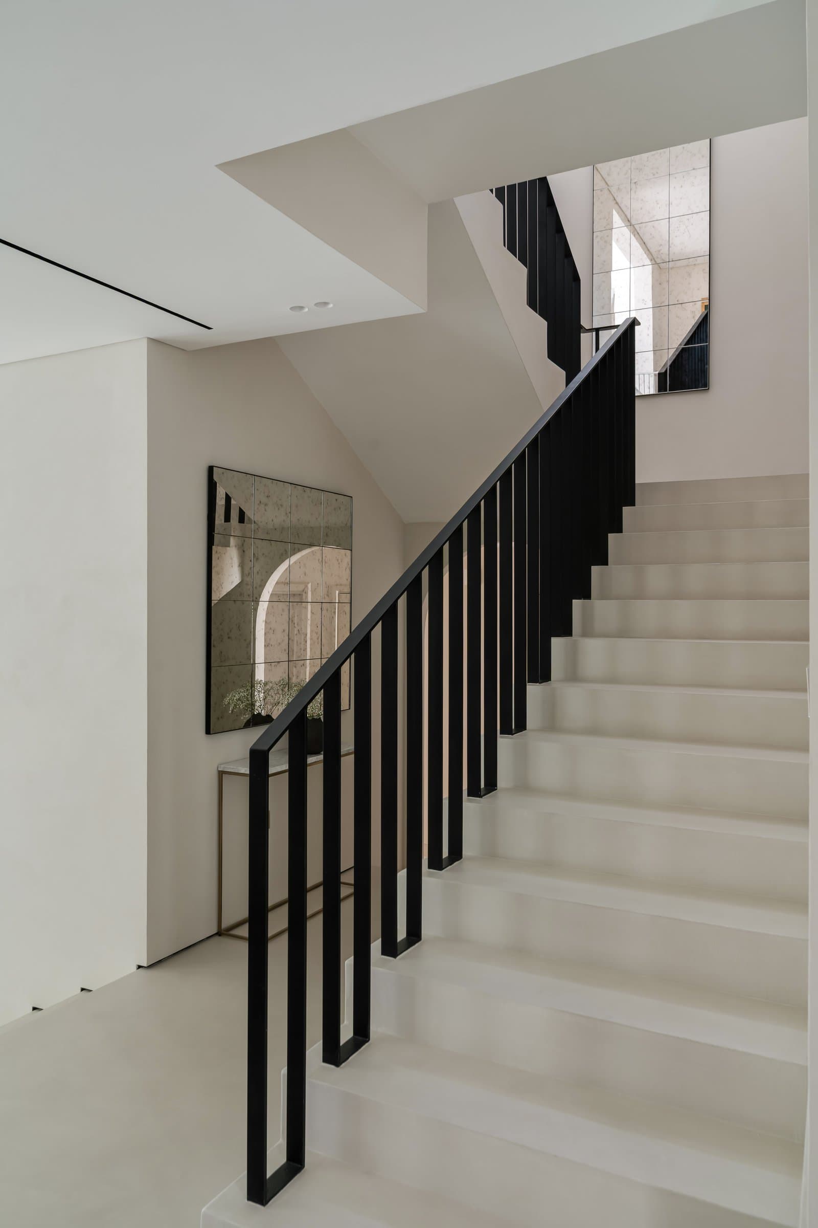 An antiqued mirror at the landing reflects light back into the double-height void