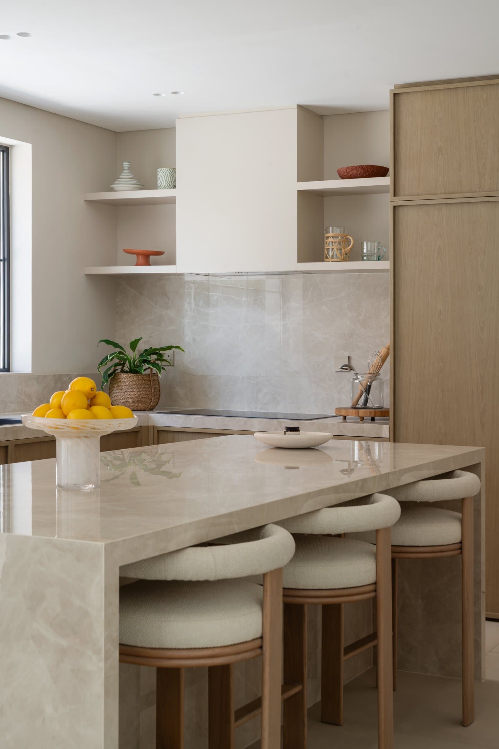 The kitchen, where oak cabinetry, a marble island, and a plaster range hood read as architecture rather than appliance