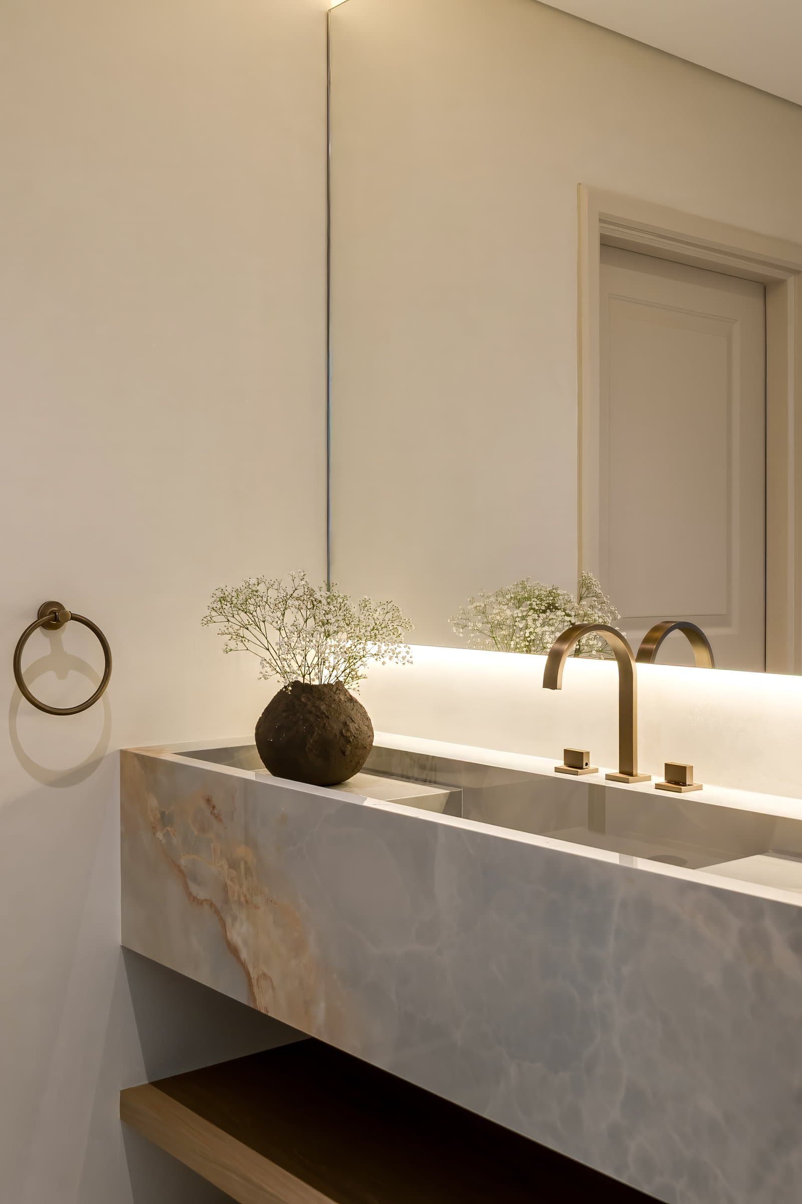 The powder room vanity is carved from onyx, backlit so the amber veining glows from within