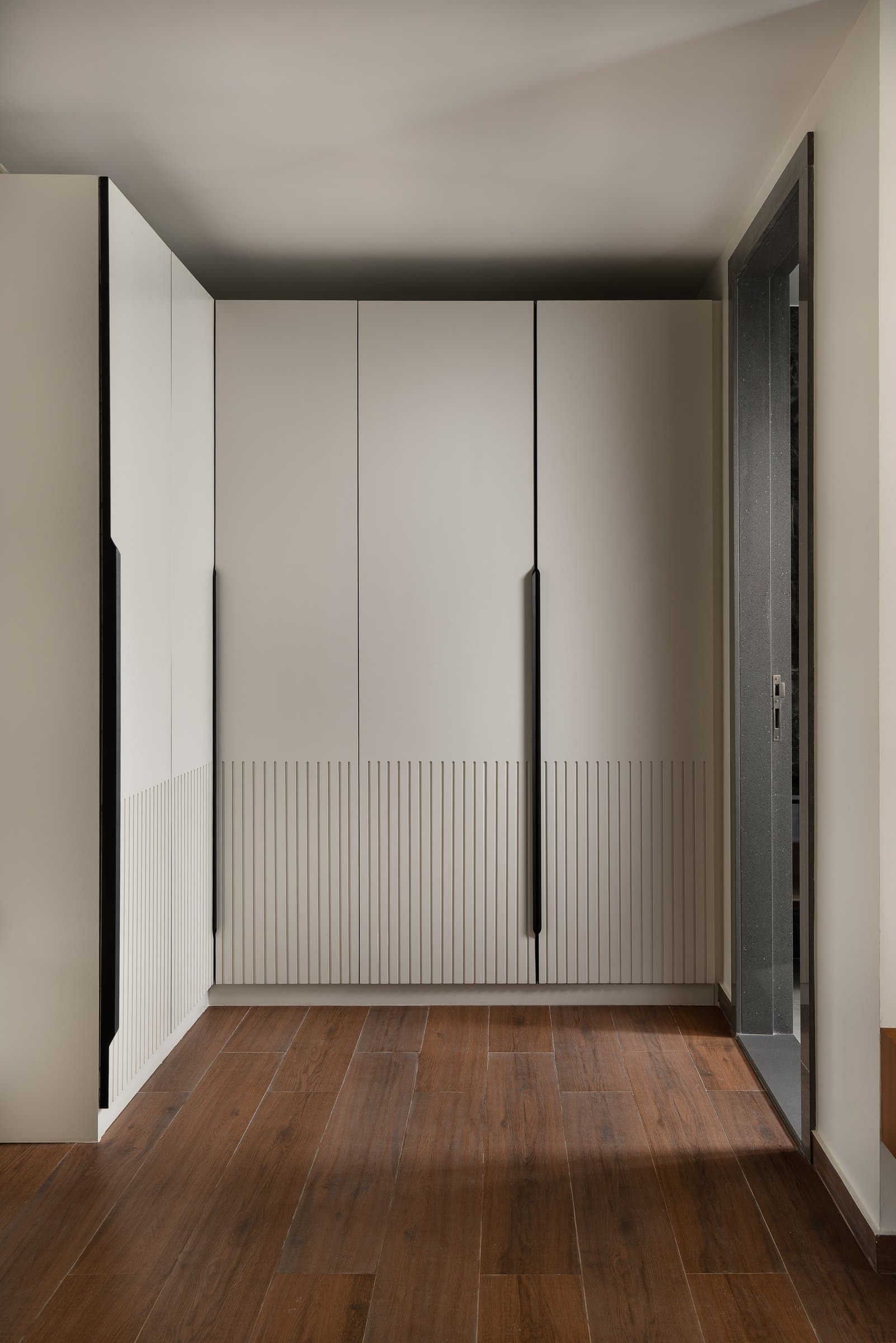 The wardrobe vestibule, reduced to matte cabinetry and a dark plank floor