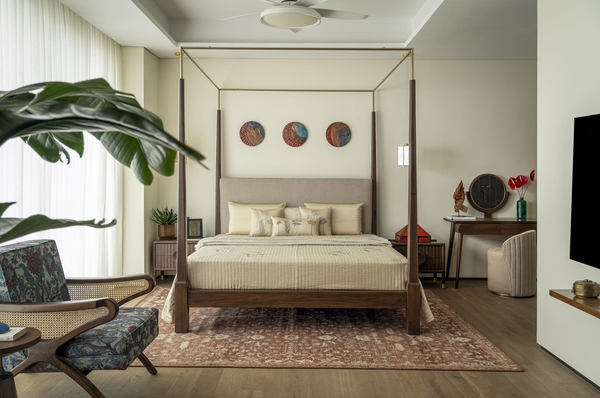 The master bedroom: a dark wood four-poster, three ceramic discs above, and the room reading as a thoughtful arrangement rather than a matched set