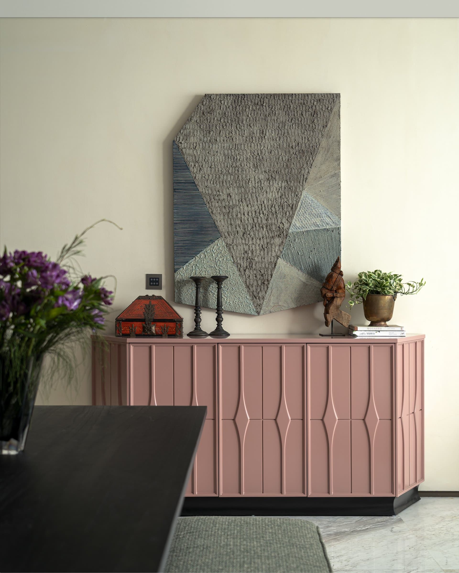 The rose sideboard with its panelled geometry, paired with a slate-toned textured artwork