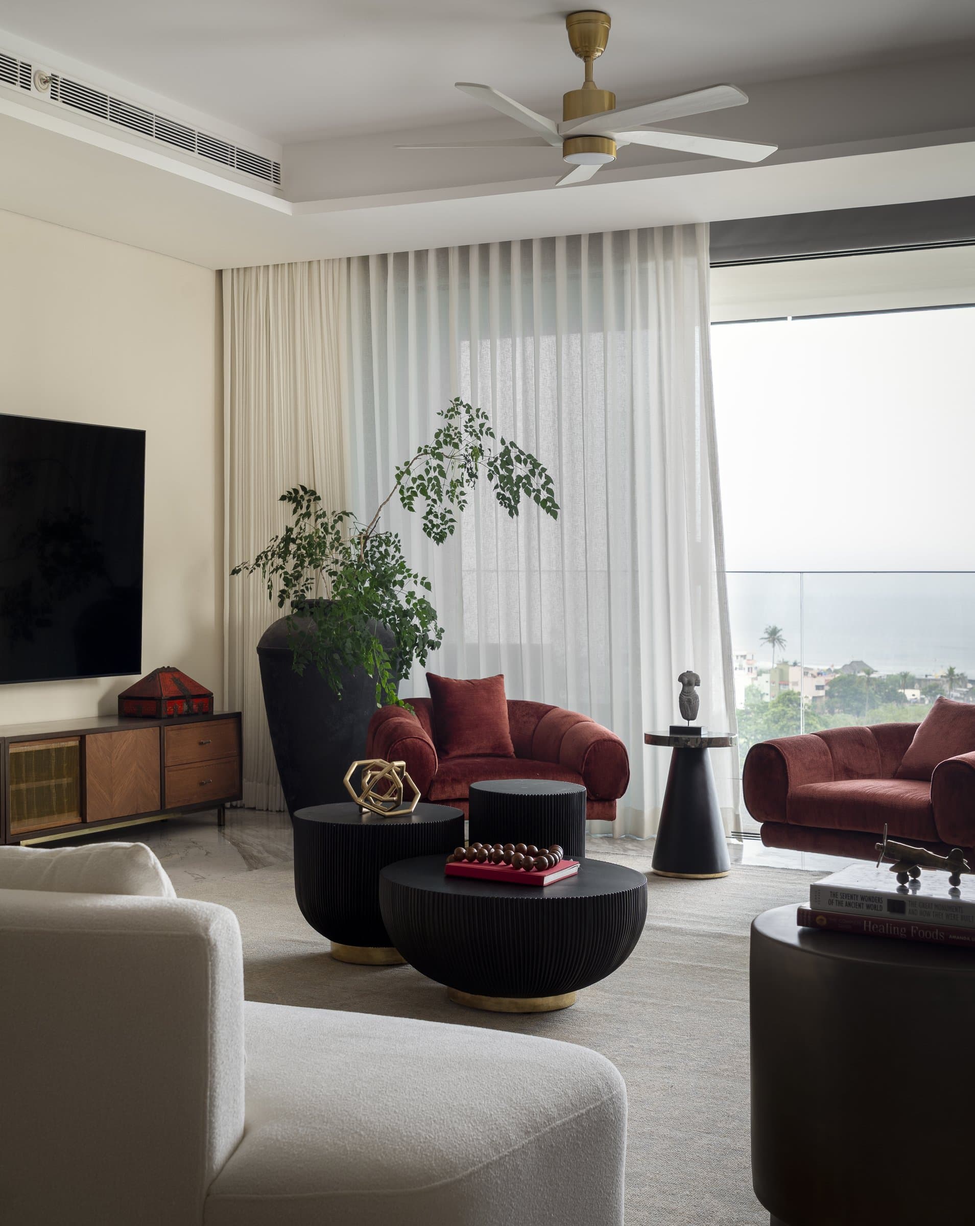 A second view of the living room, where a low cane-fronted console and a tall matte vessel form the room's quiet pause