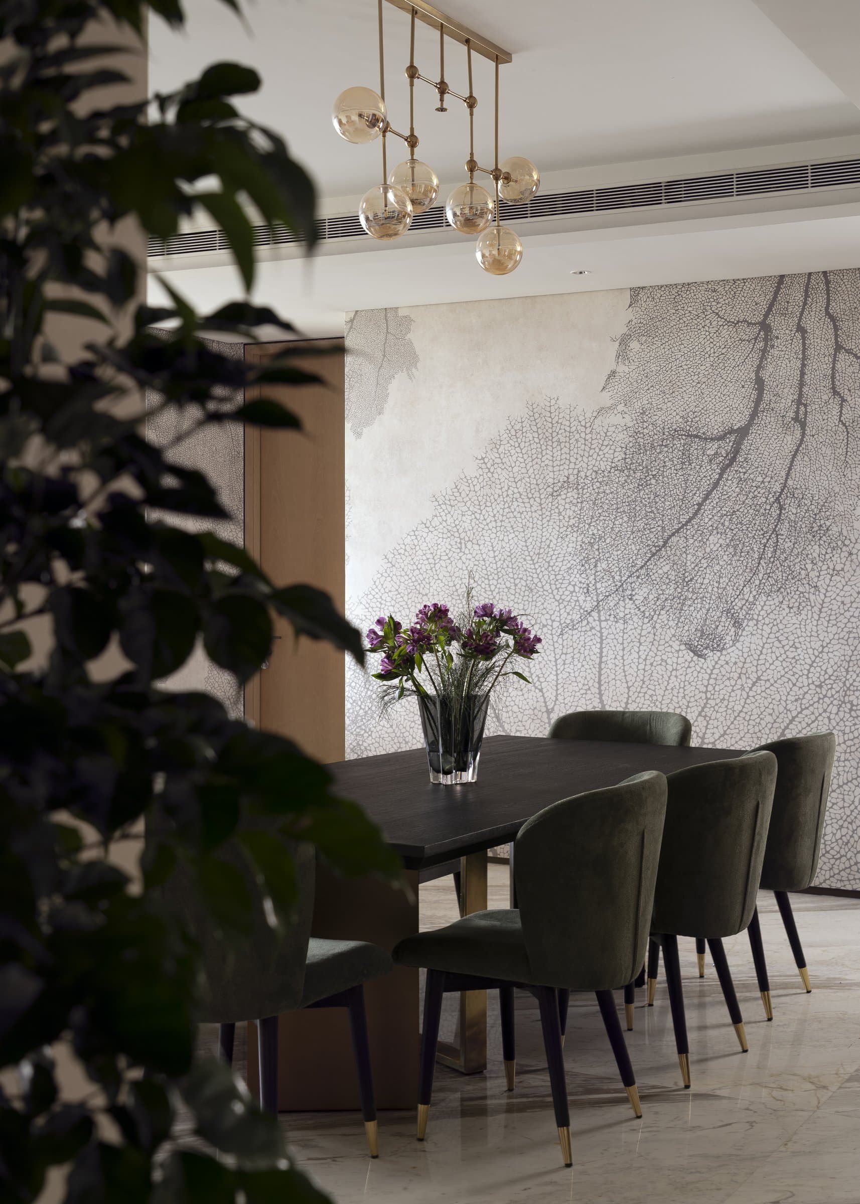 The dining table seen through foliage, the mural wall connecting it back to the living room