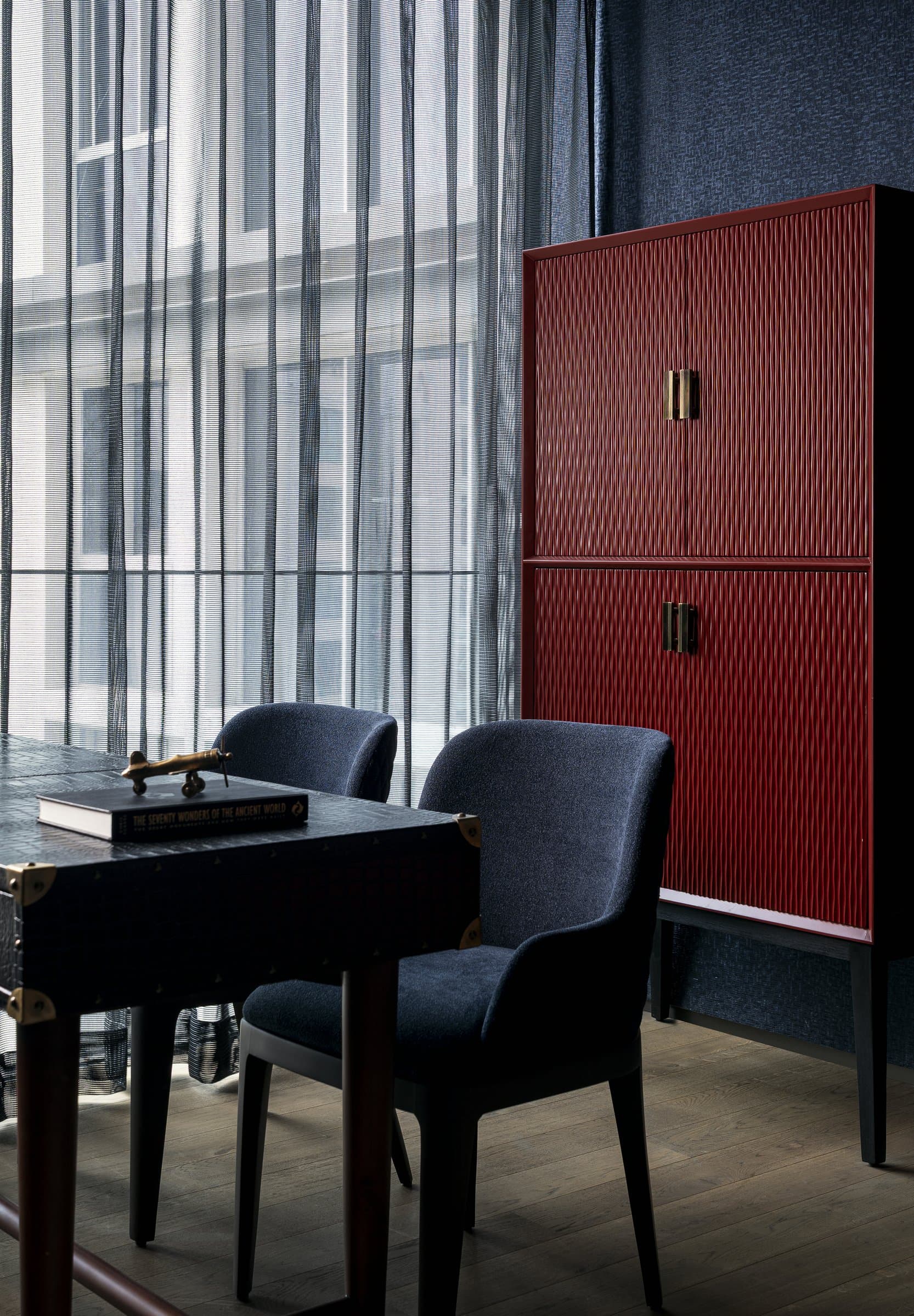 The study's red fluted cabinet, a piece of furniture that has chosen to be architecture