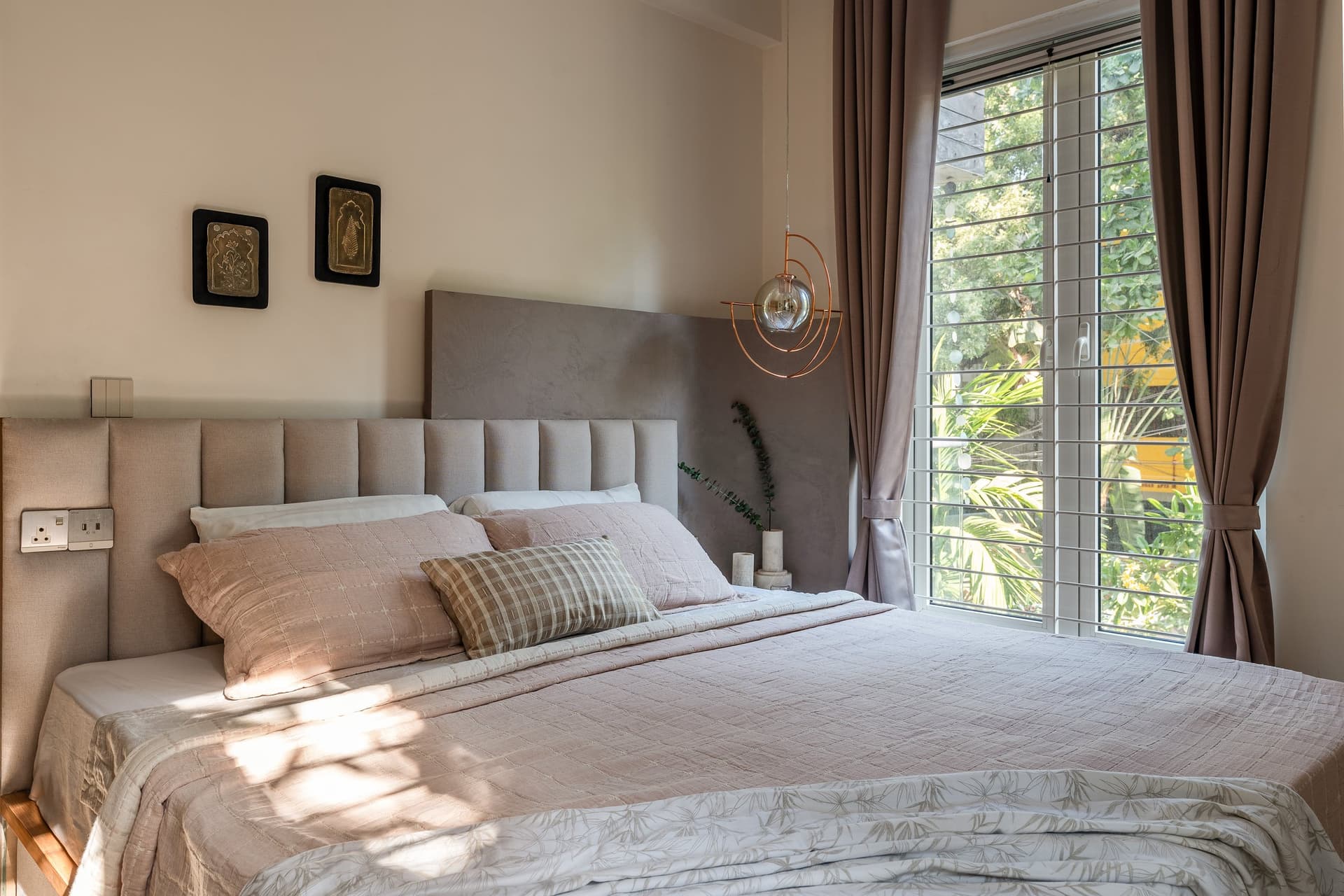 The master bedroom, a channel-tufted headboard and matte grey plaster creating a calm textural counterpoint