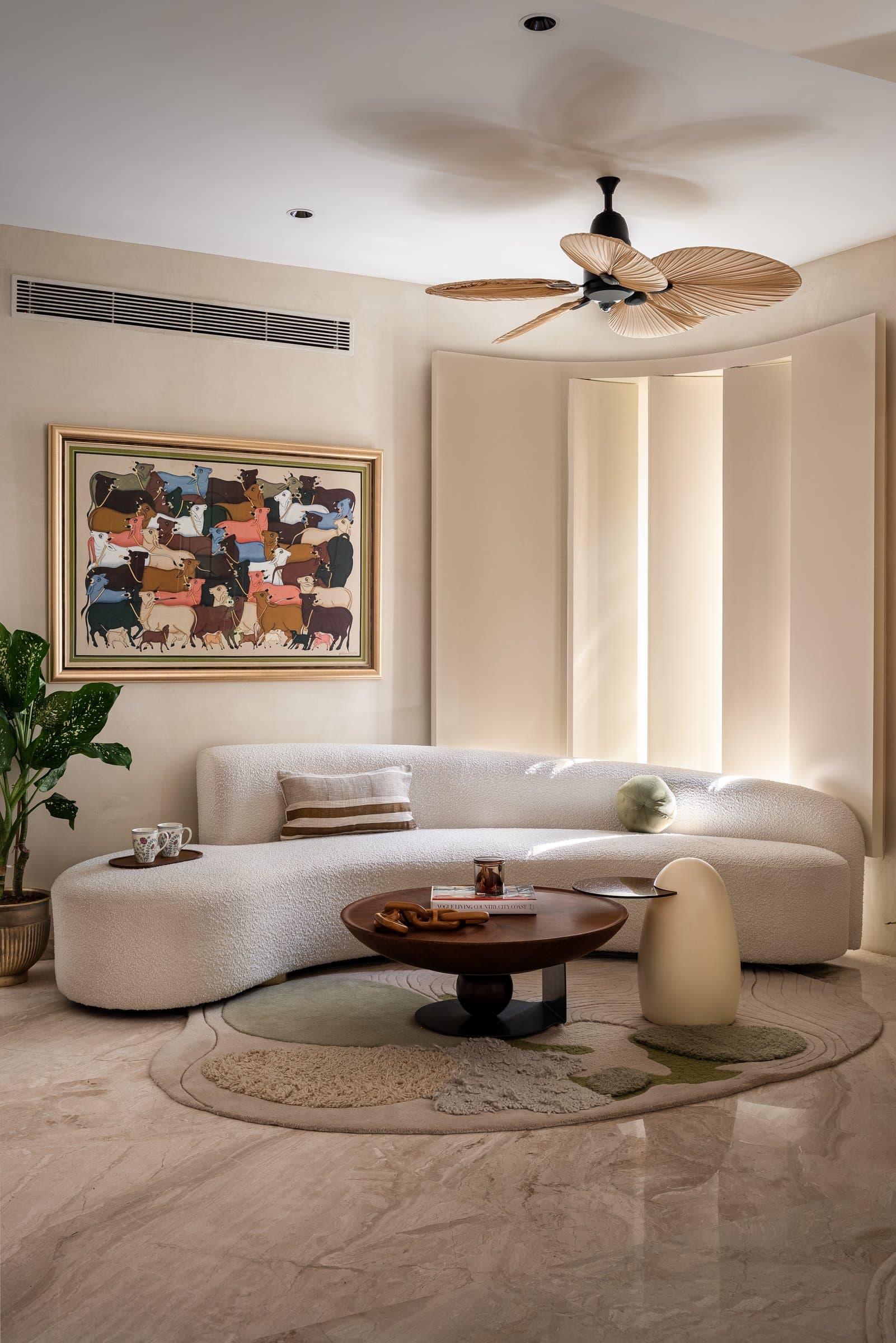 A closer view of the seating group, the sofa's soft geometry meeting a pedestal timber table on a hand-tufted rug in cream and sage
