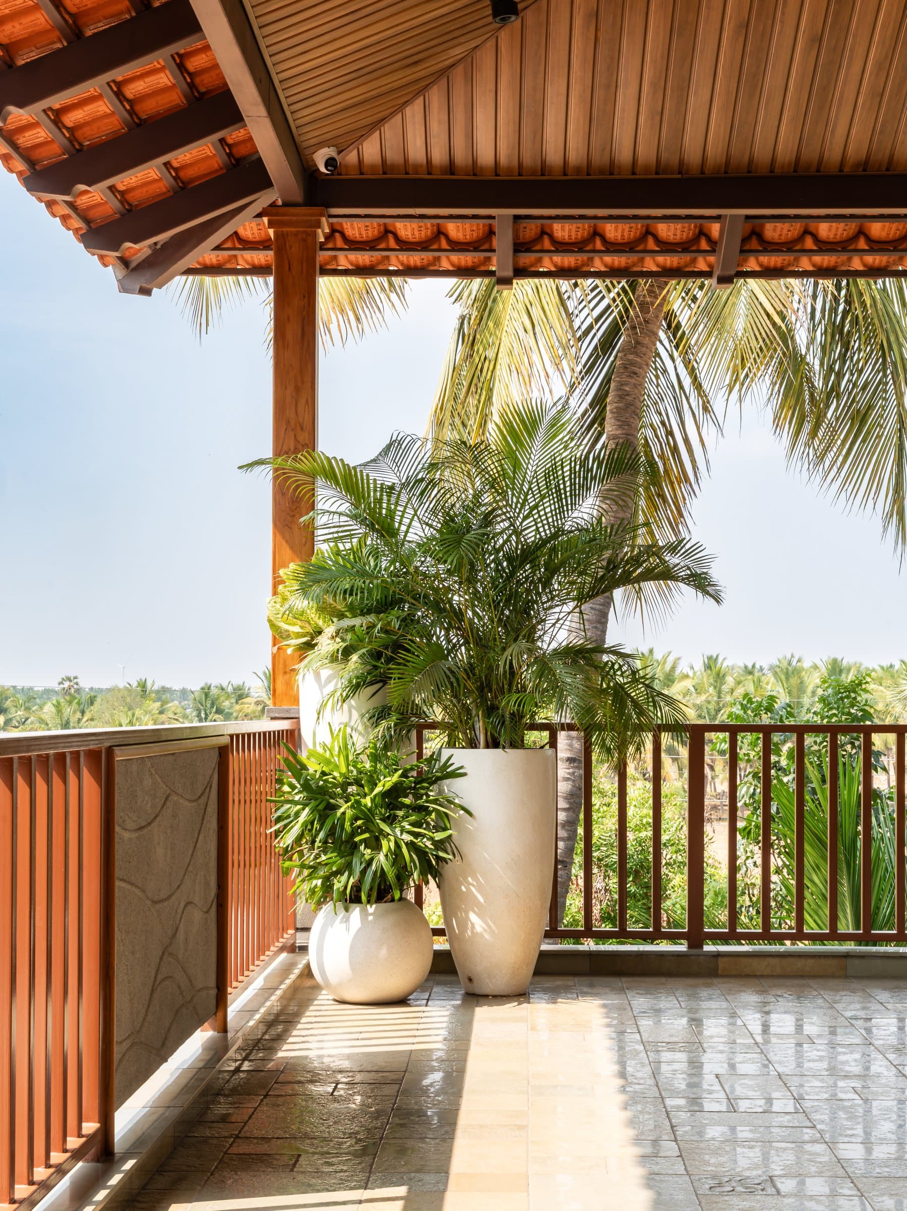 The upper balcony, sheltered by a timber-lined Mangalore-tile roof over a stone-flagged terrace