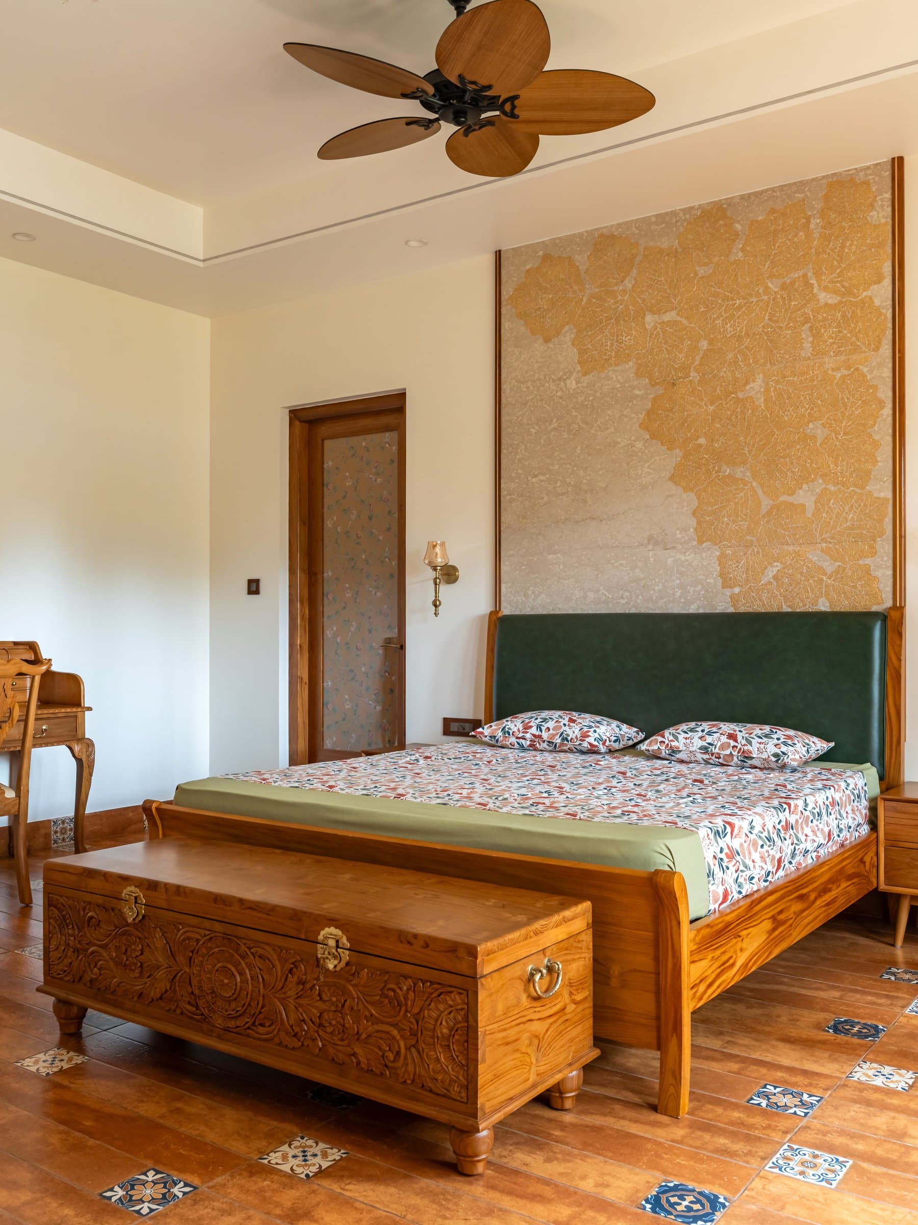 The master bedroom, where a hand-carved timber chest and tile-inlaid flooring extend the craft palette underfoot