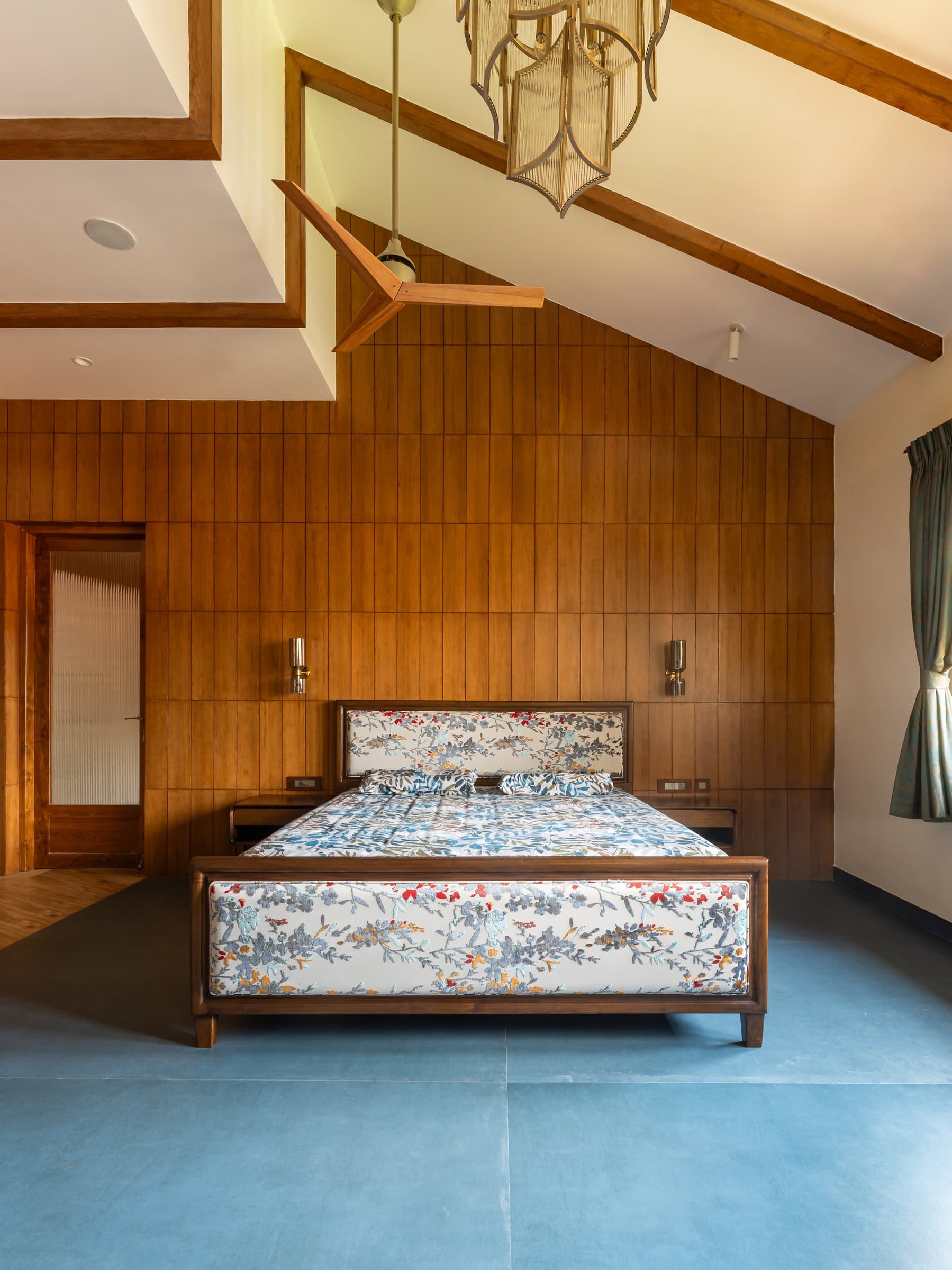 The upper-floor bedroom, where a pitched timber-clad ceiling with exposed beams follows the roofline